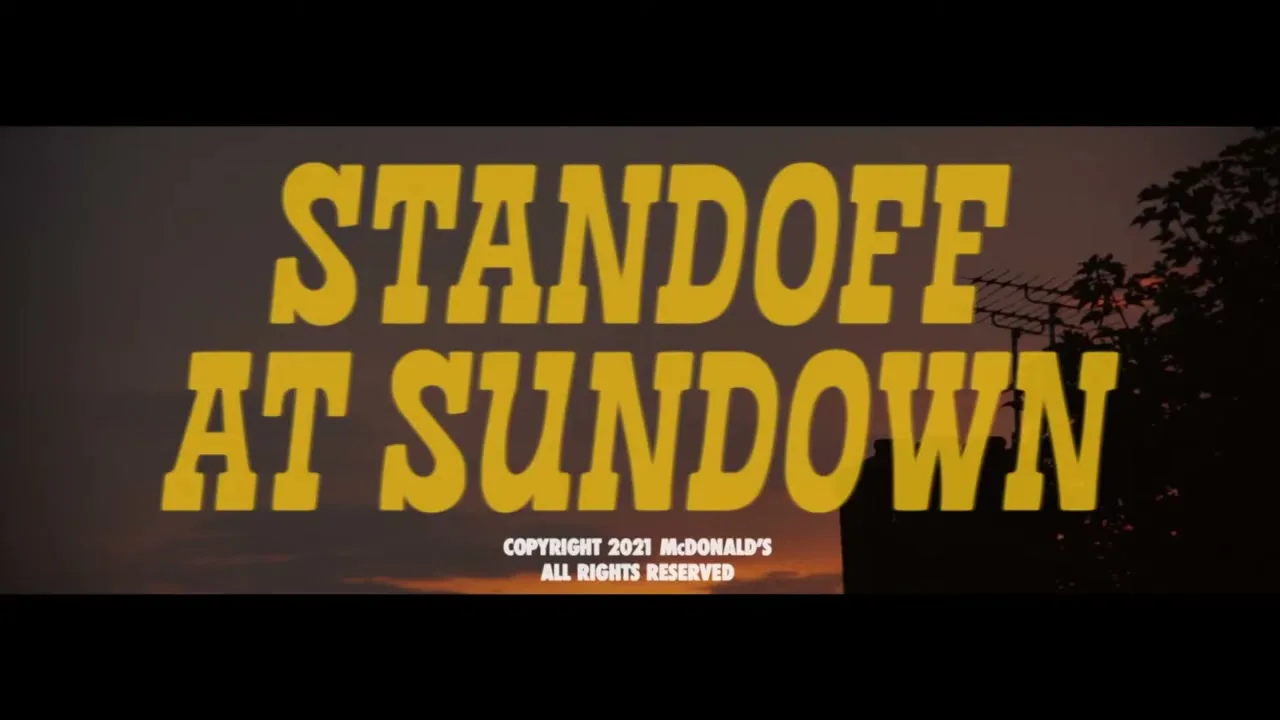 A title card for "Standoff at Sundown" is displayed in yellow text against a sunset sky with silhouetted trees and buildings.