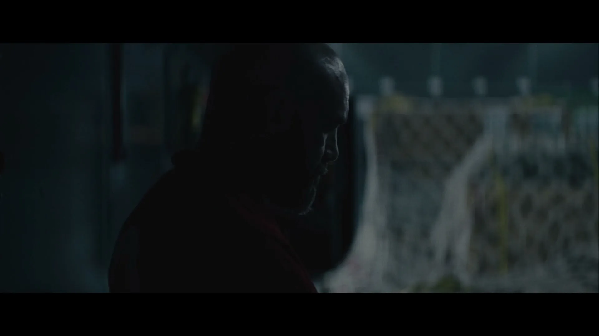 A man in a red uniform writes on a clipboard inside a dark cargo plane, then turns and walks away.