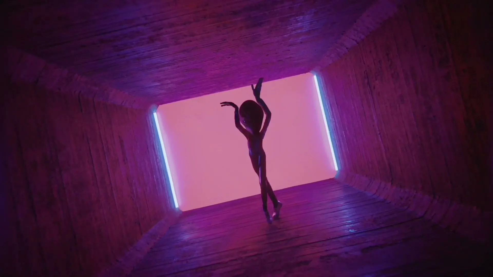 A small, dark alien figure with large eyes dances in a pink-lit tunnel with blue neon lights on the sides.