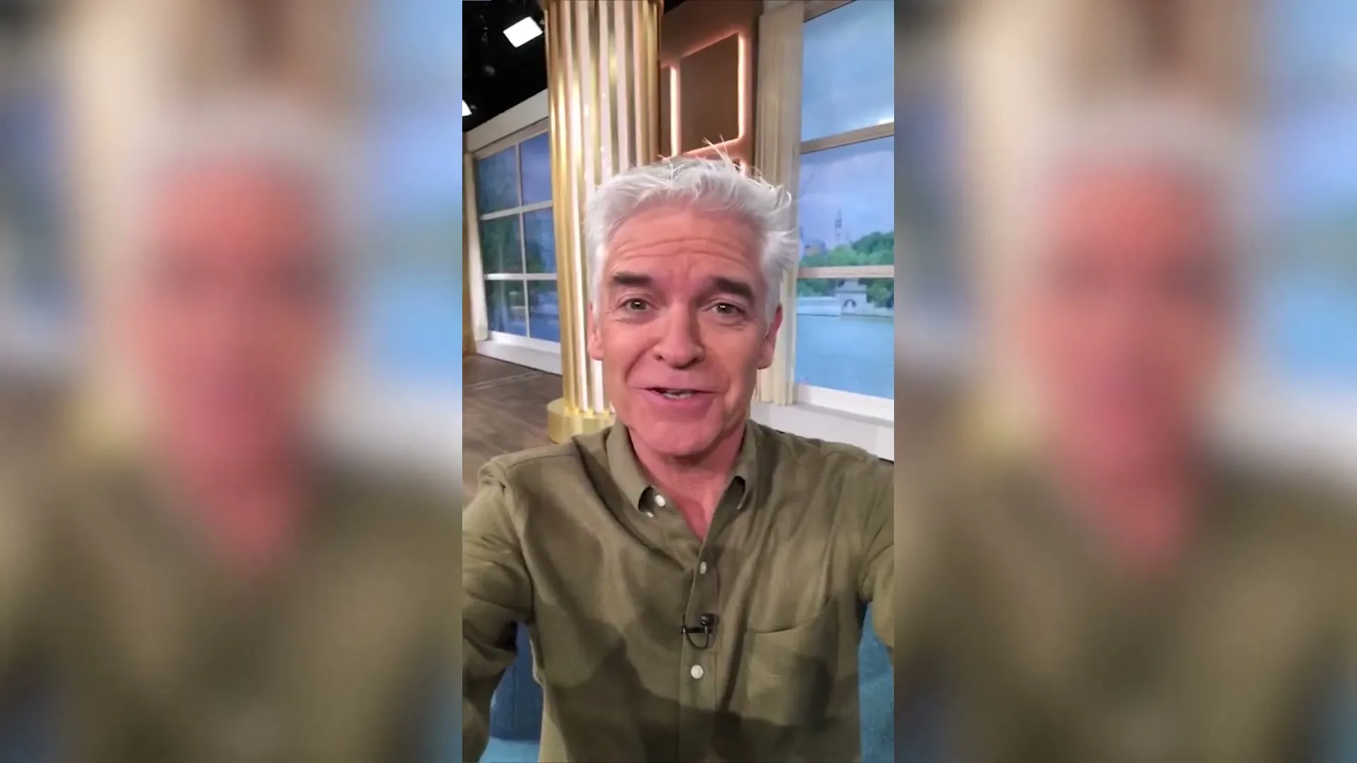 A middle-aged man with grey hair and a green shirt talks directly to the camera in a TV studio, with a blurred background.