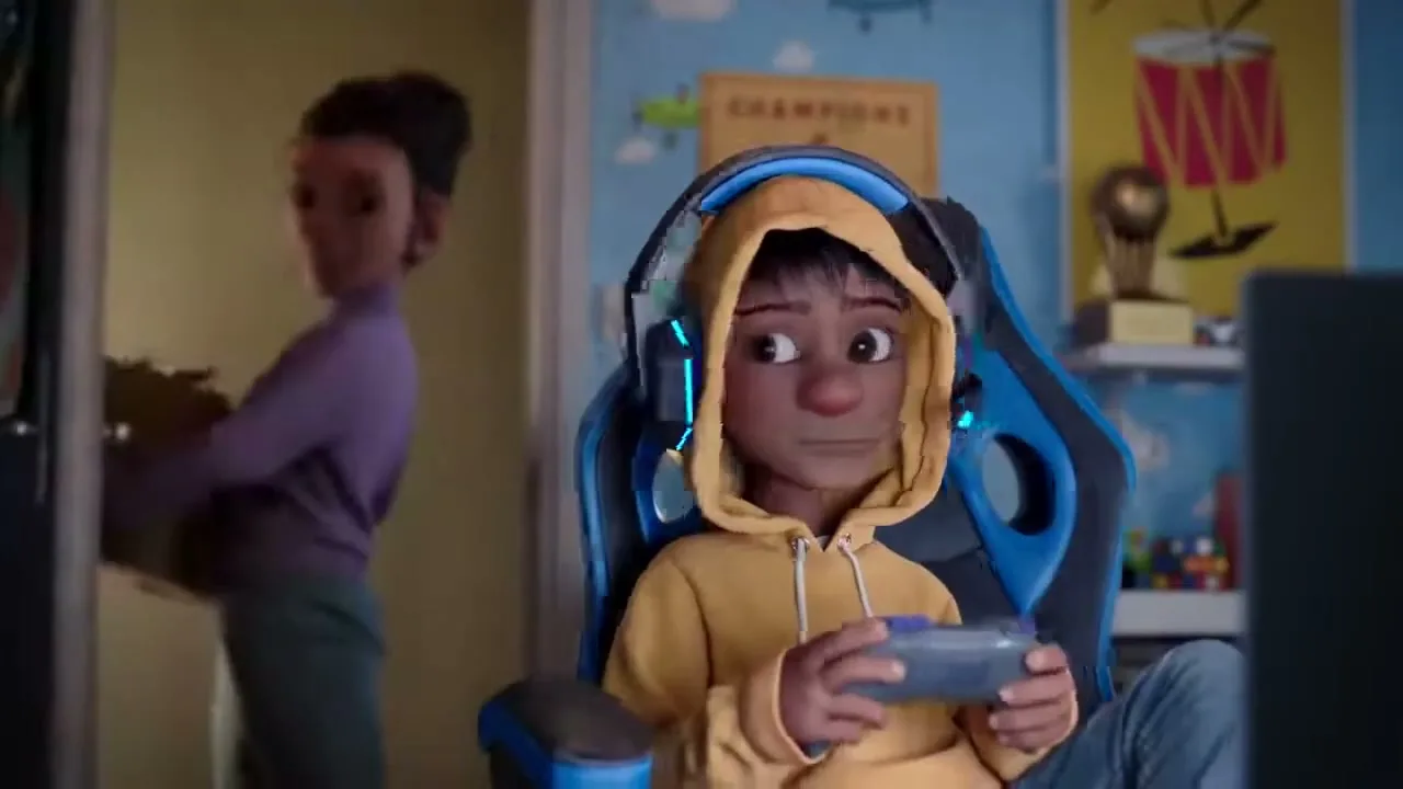 A young boy in a yellow hoodie and blue headphones plays video games in his room, as a woman carrying a box of decorations enters.