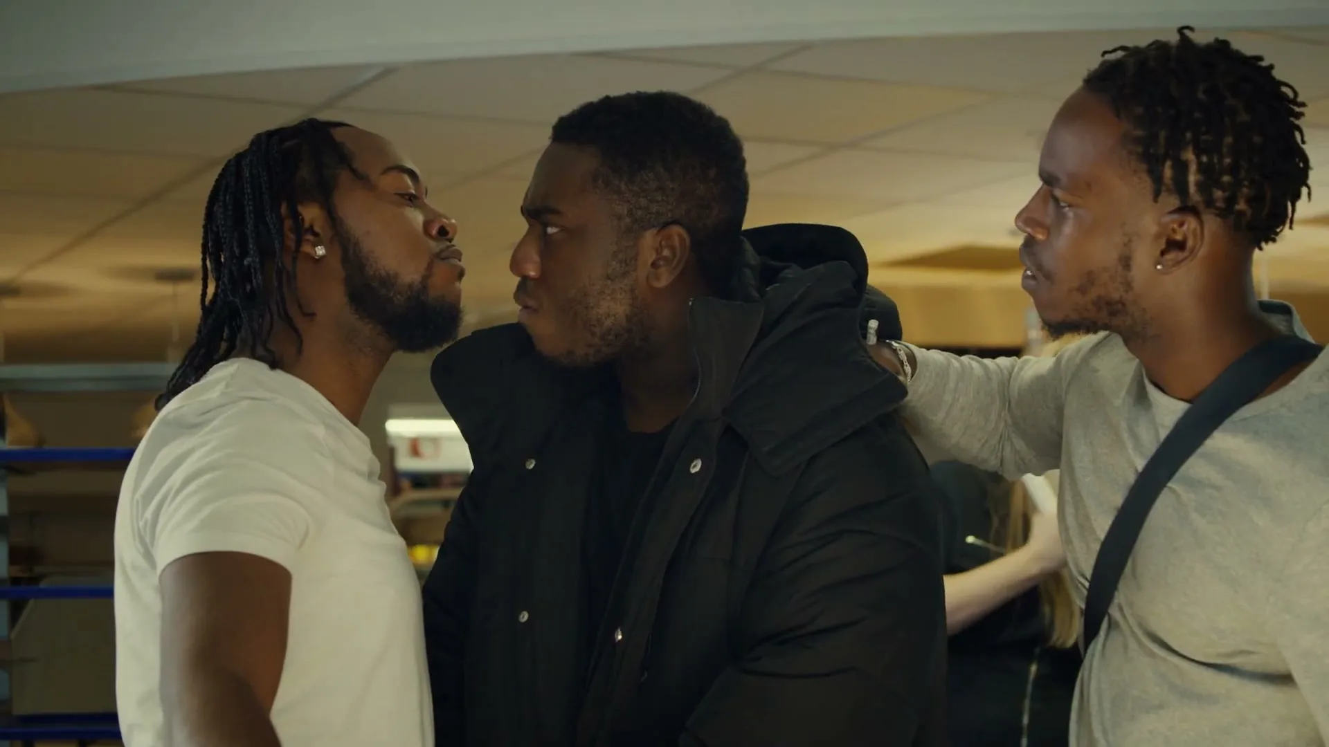 Two men with dreadlocks face each other in a boxing ring, appearing to argue, while a third man tries to intervene, in an interior boxing gym.