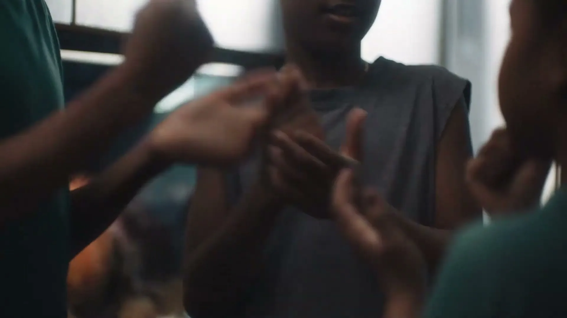 Three children with dark skin play a hand-clapping game, their hands moving quickly in a close-up shot inside a home.