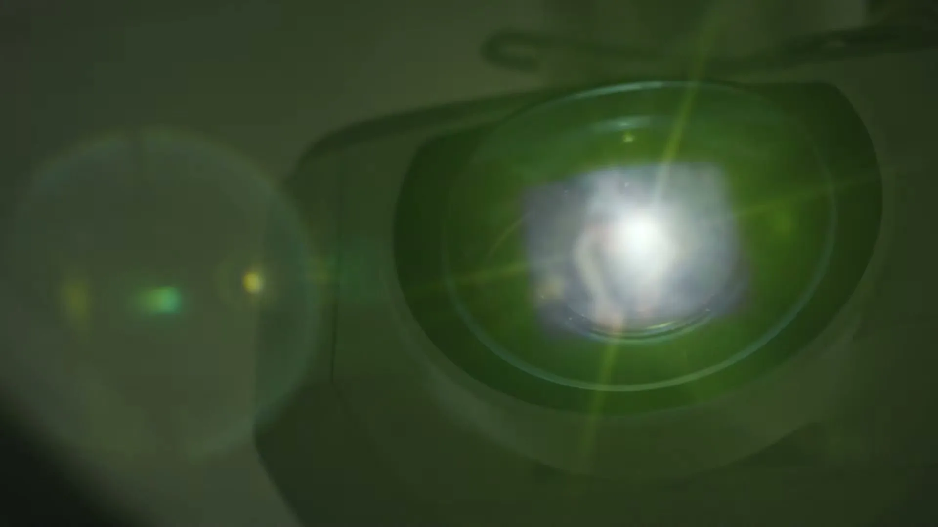 A close-up shot of a projector lens, with a bright light shining from it, in a dark room.