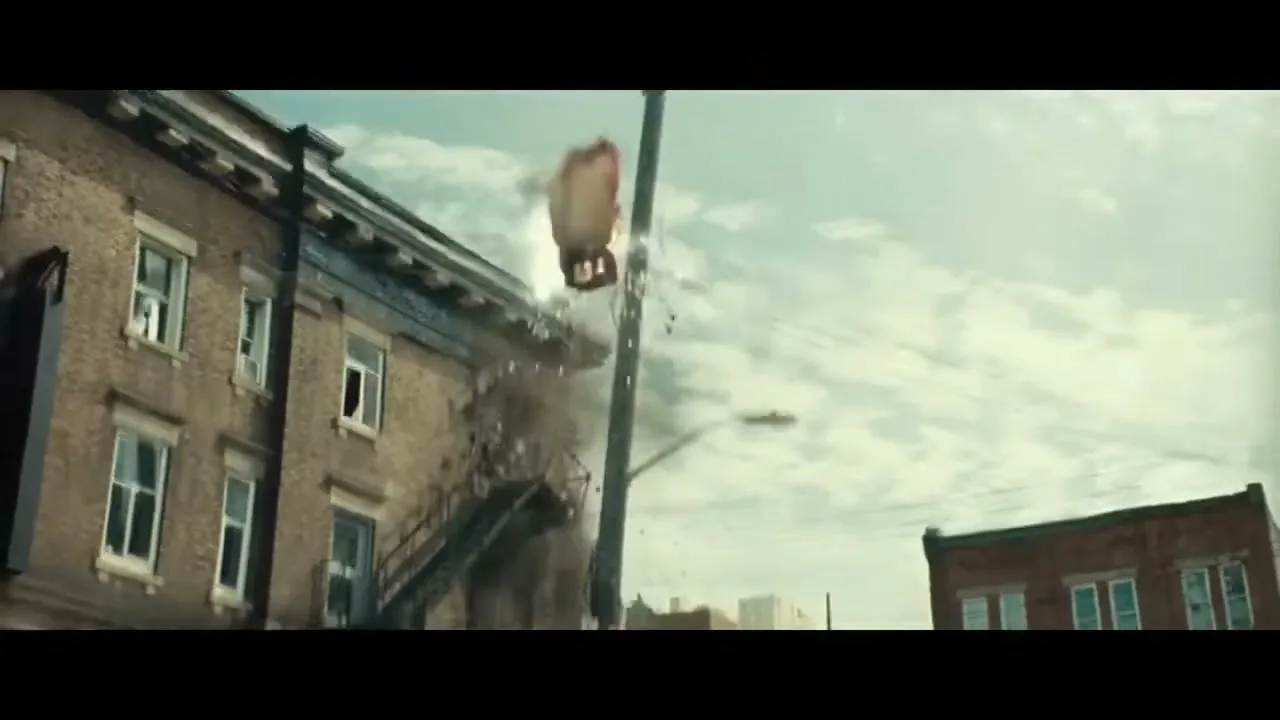 A superhero in a red cape and blue suit crashes into a car, creating a dust cloud, while another superhero in gold armor lies on the ground in a destroyed city street.