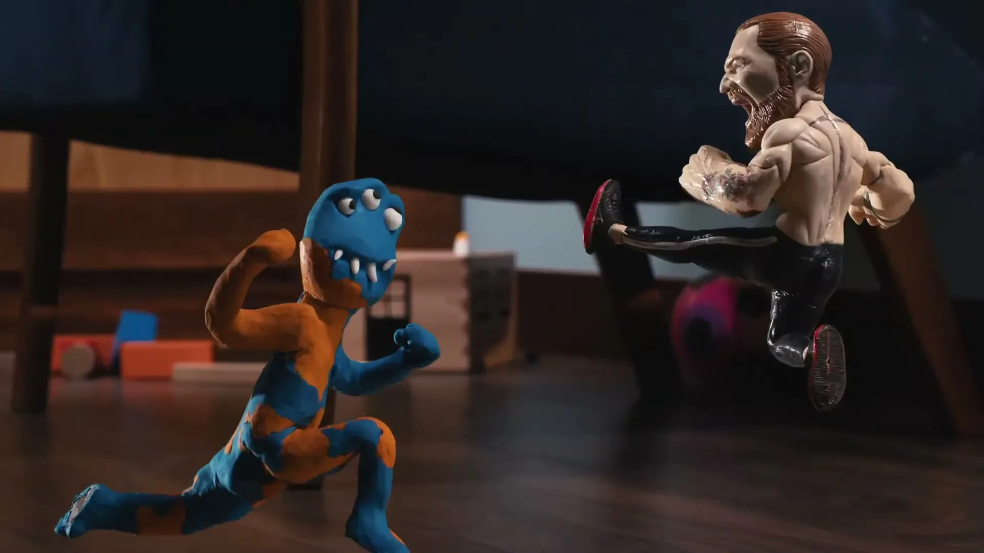 A stop-motion animated action figure of Conor McGregor fights a blue and orange clay monster on a wooden floor under a chair.