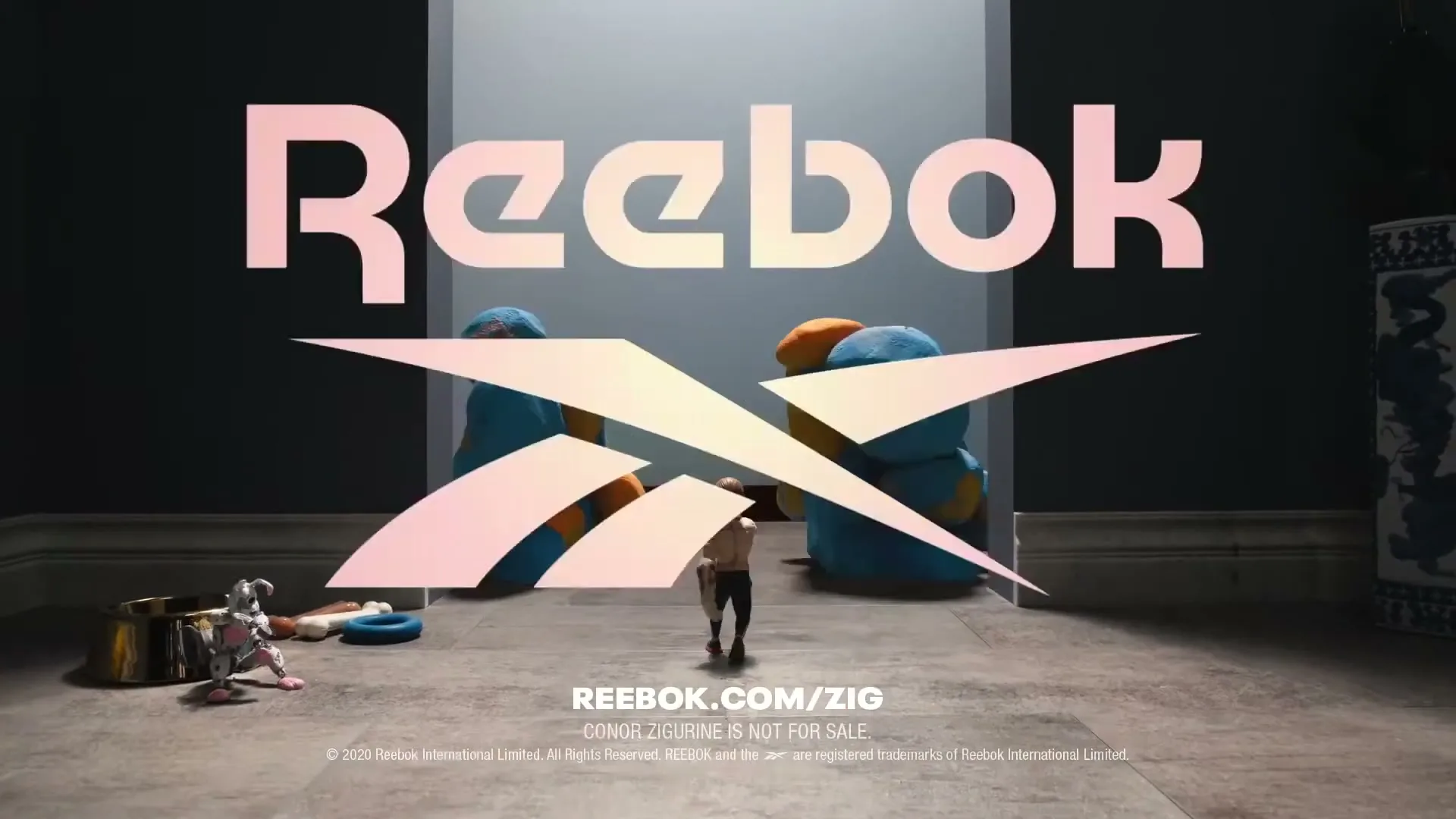 A small, animated male figure runs towards the camera as a large, colorful, amorphous creature grows behind him, with the Reebok logo appearing in the center.