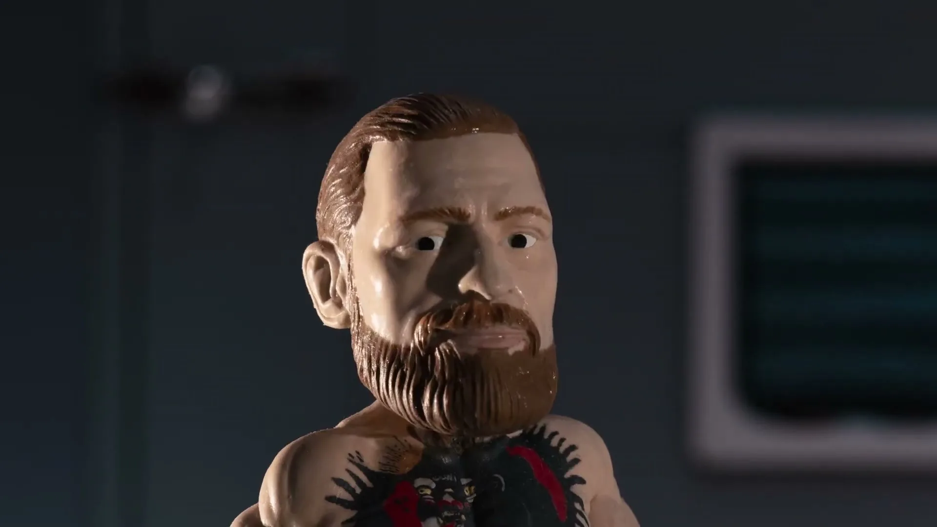 A bobblehead of Conor McGregor with tattoos on his chest looks around in a dark room.