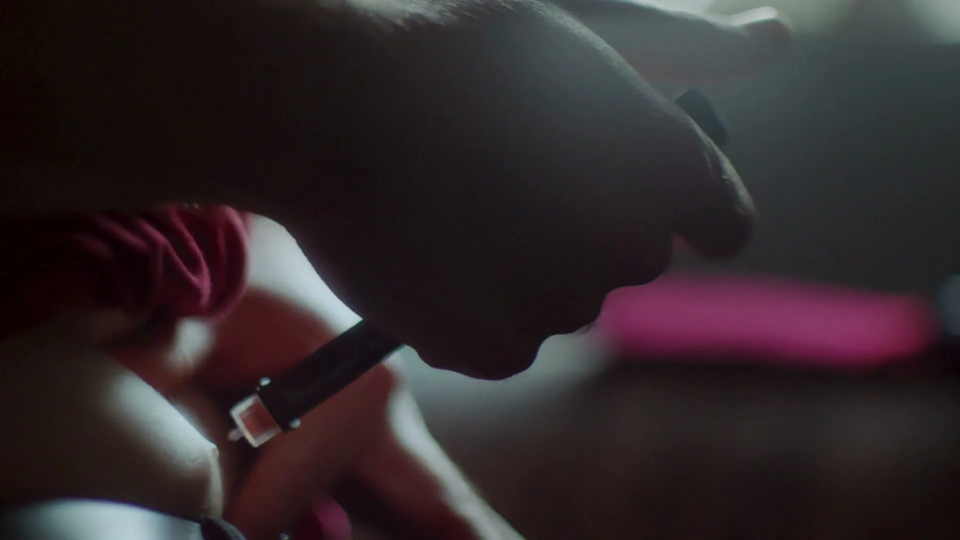 A person's hands are shown in a medium closeup, adjusting a medical device on their body in a dimly lit interior setting.