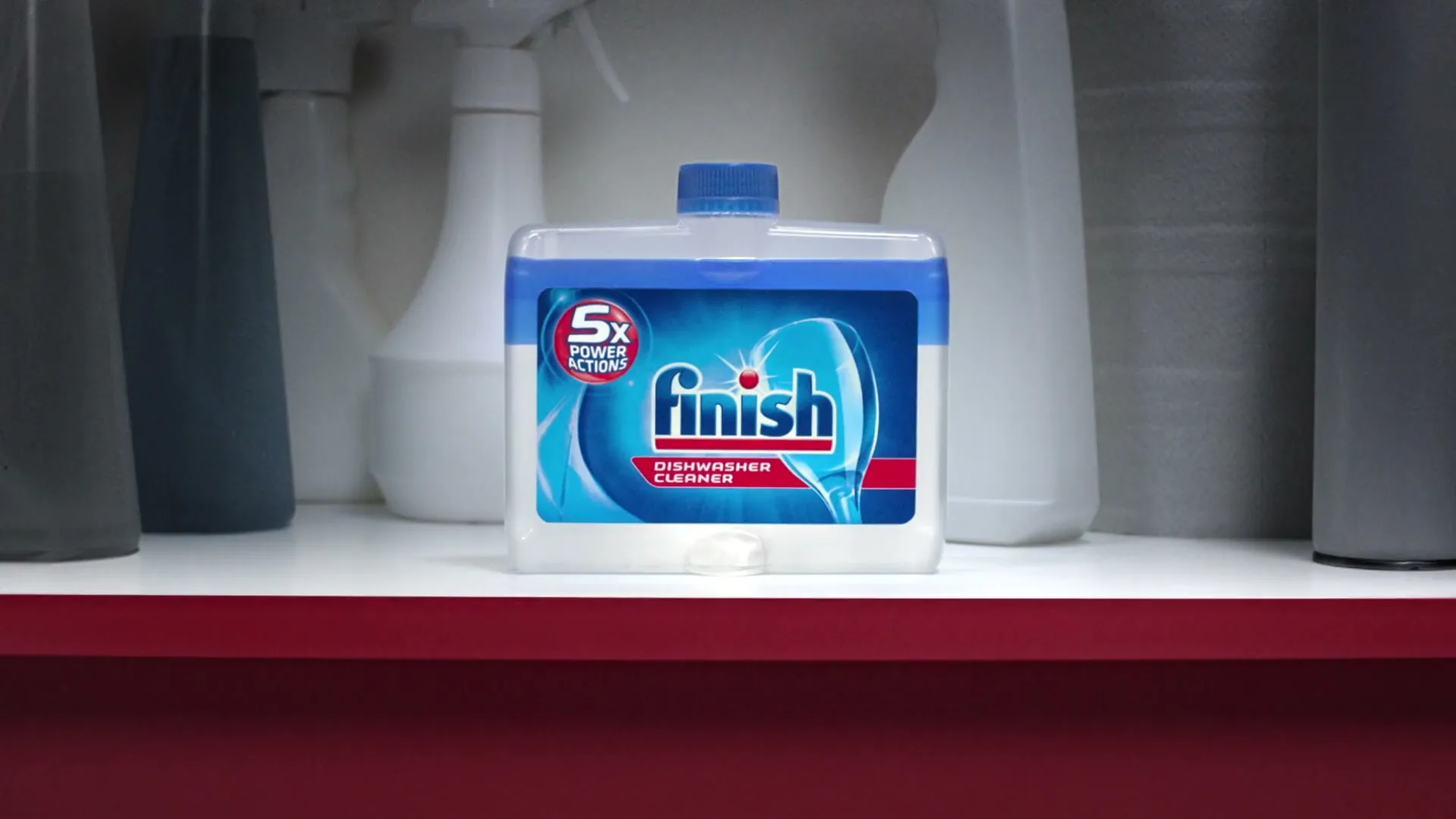 A pair of hands opens a red cabinet to reveal a bottle of Finish Dishwasher Cleaner on a shelf with other cleaning supplies.