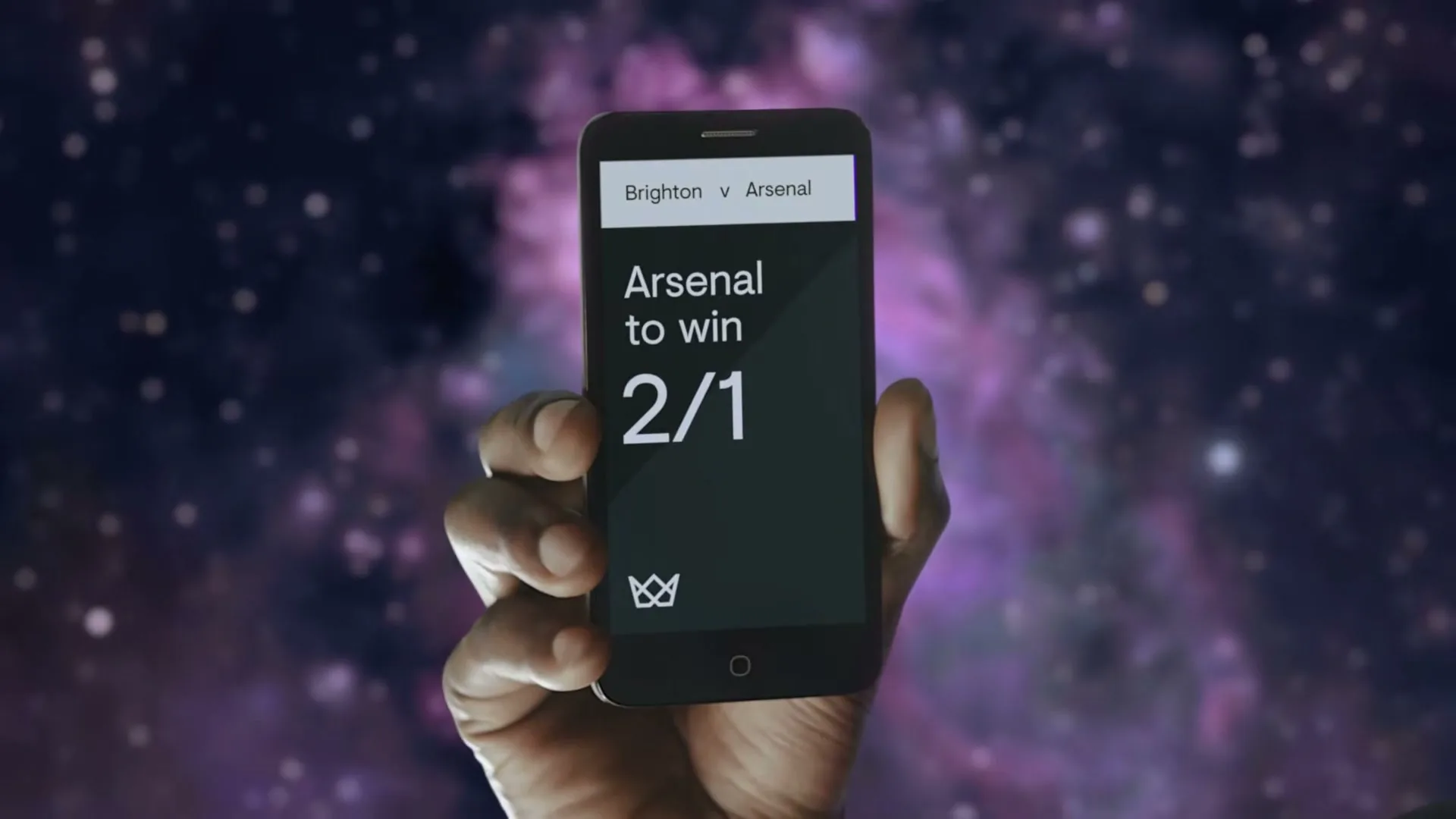 A person's hand holds a smartphone displaying a betting app with odds for a football match, against a cosmic background.