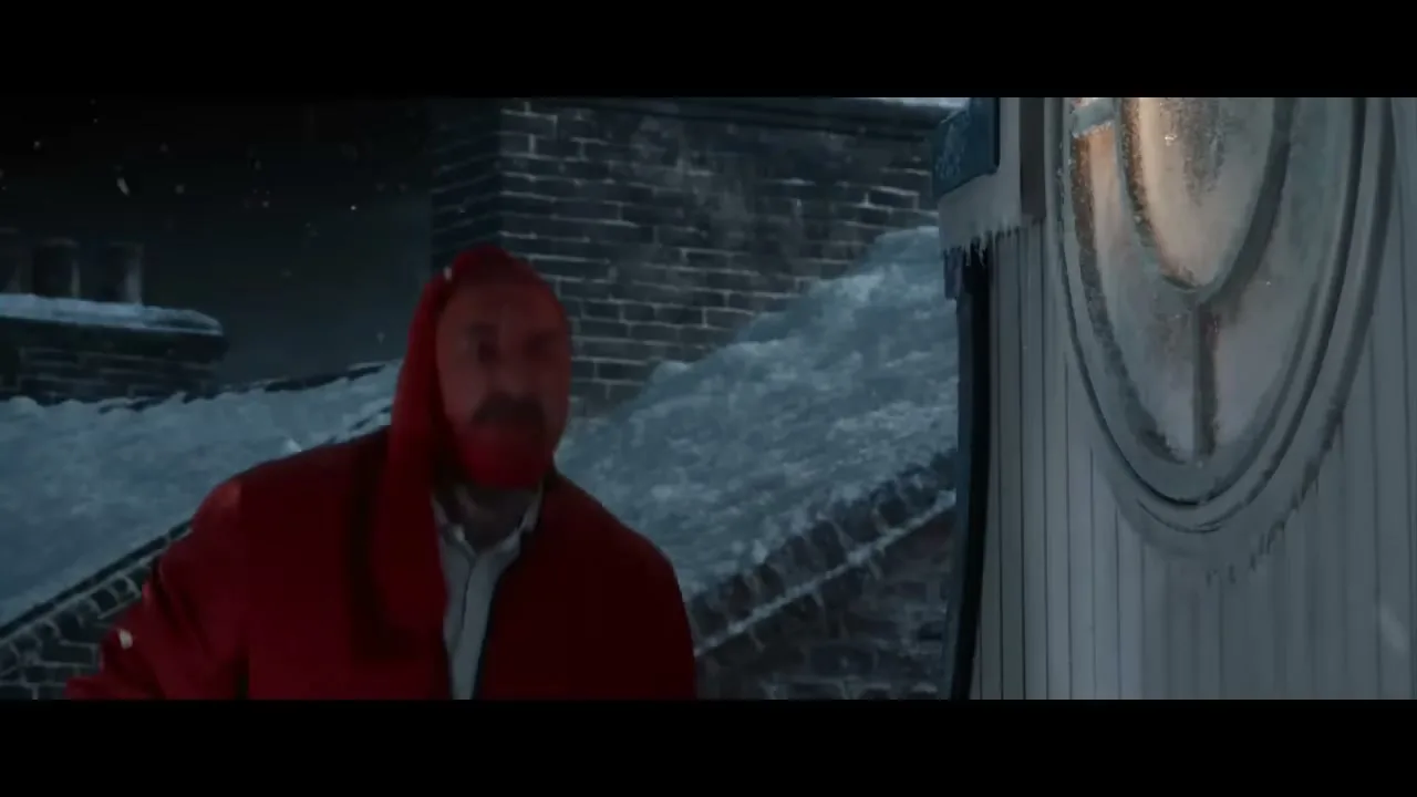 A man dressed as Santa Claus is on a snowy rooftop at night, looking surprised as a bear in a red hat opens a window.