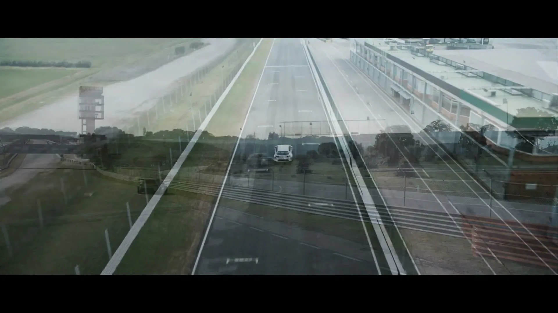 A white car is parked on a race track, while a grey race car drives past it, with a transparent overlay of another race track.