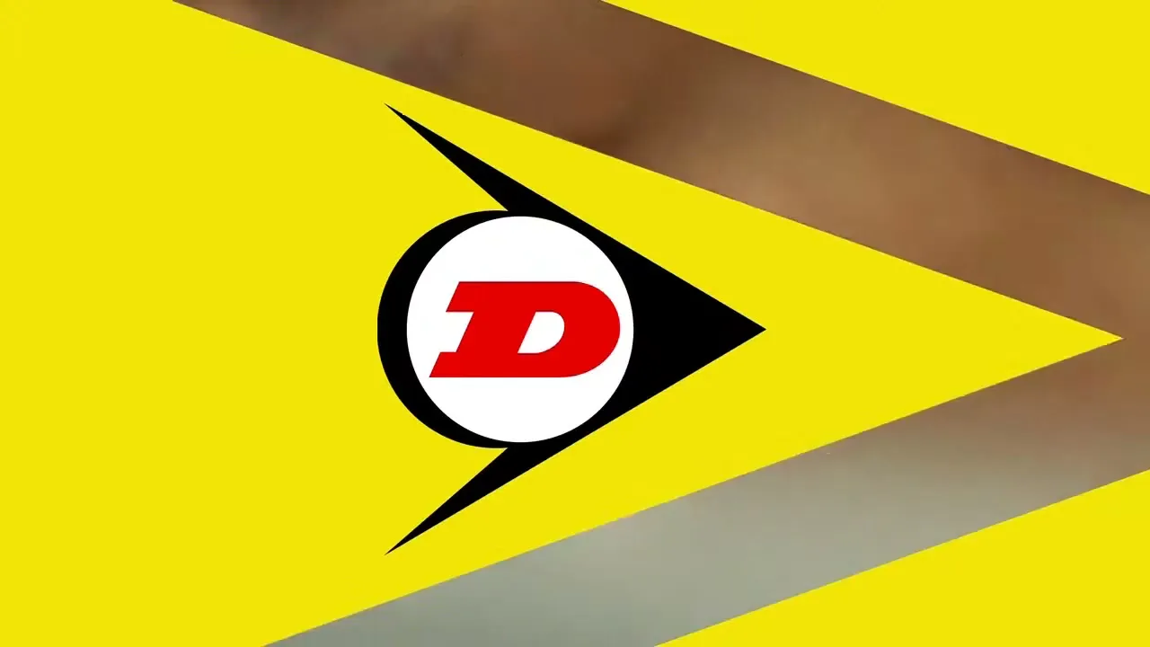 A close-up shot of a man's eye, partially obscured by a yellow graphic with a black and white Dunlop logo, as the graphic slides away.