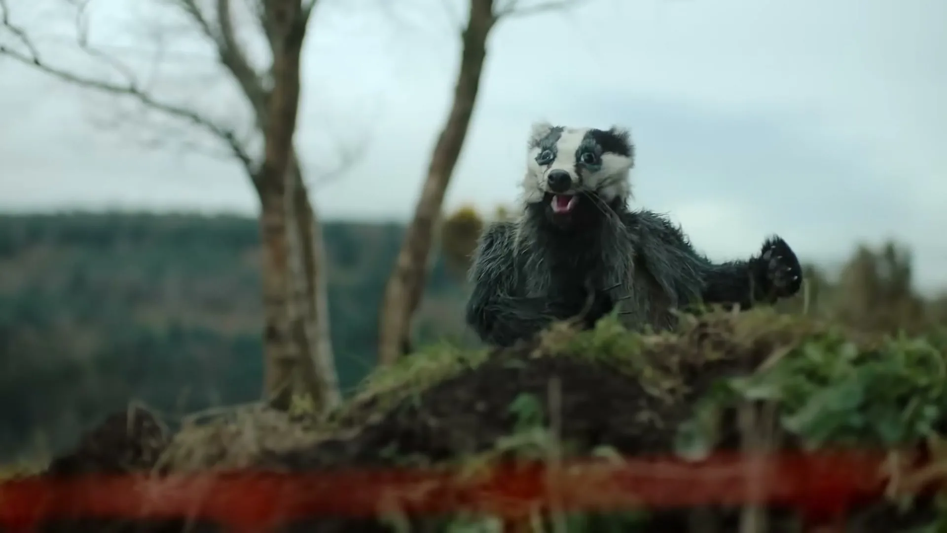 A badger puppet, covered in dirt, emerges from a hole in the ground, looking surprised and speaking about gas pipes.