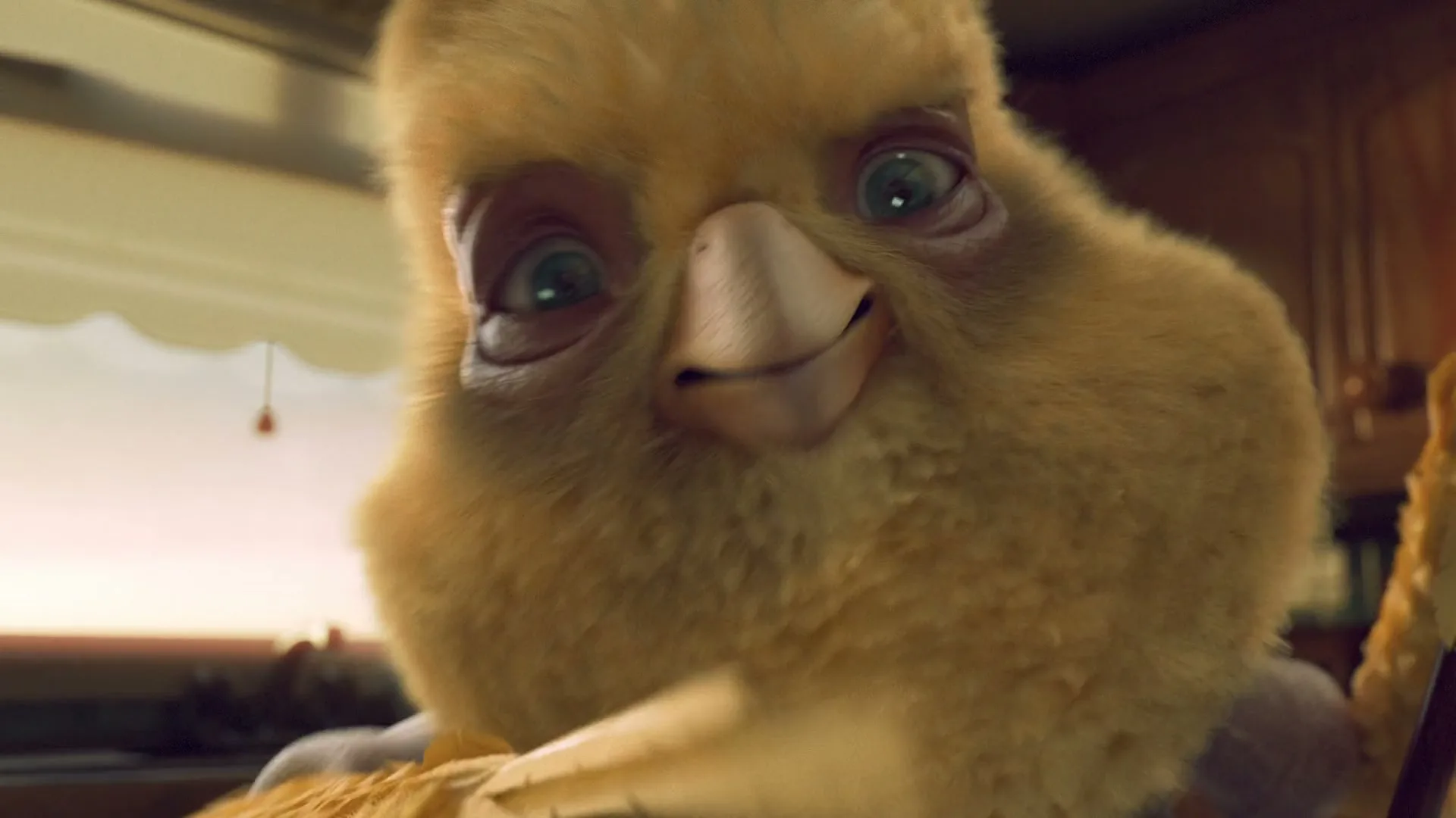 A fluffy yellow animated bird character, wearing a waistcoat, looks directly at the camera and then away, holding a feather duster in a kitchen.
