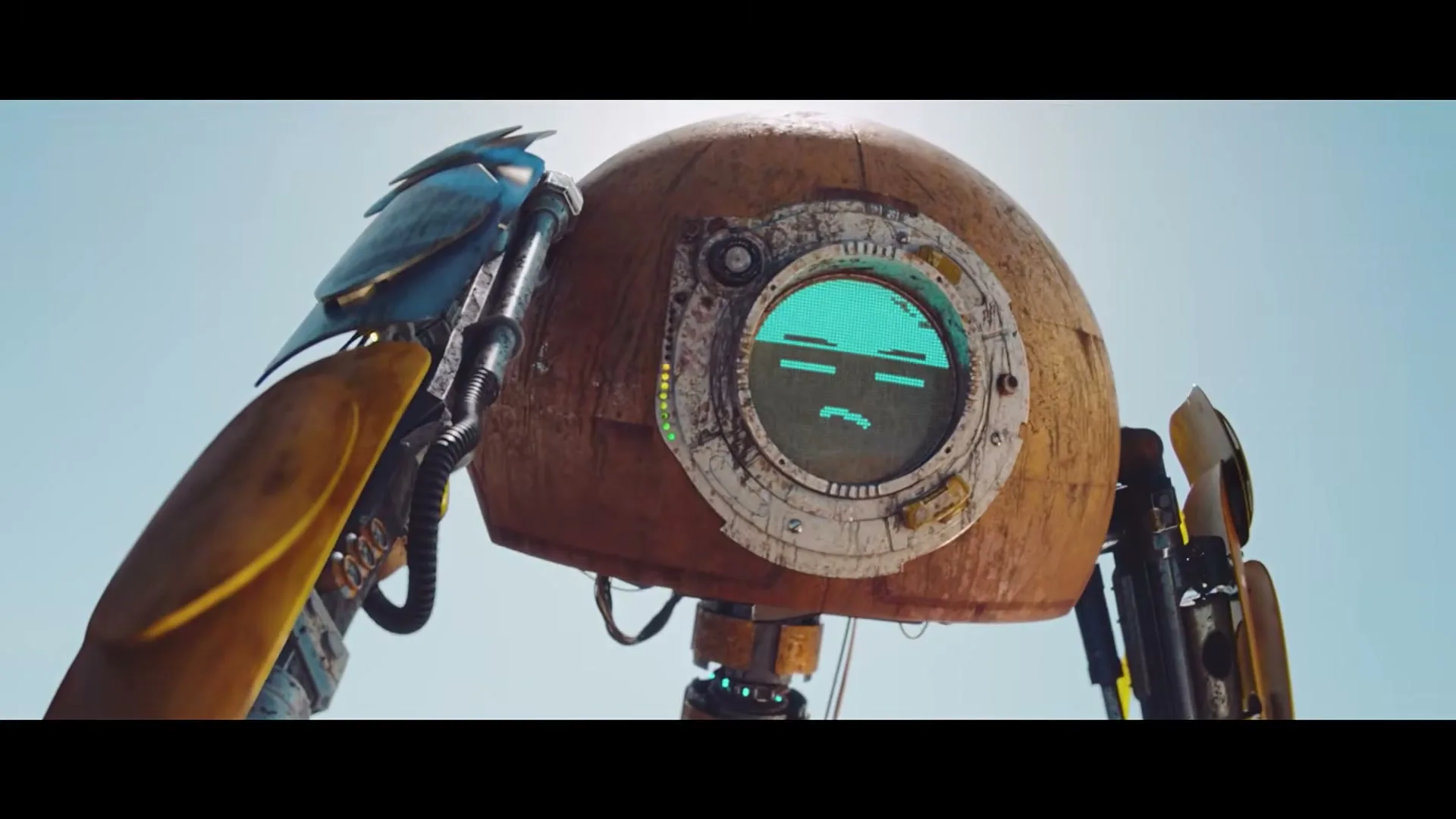 A rusty, round robot with a blue screen face and a blue bird perched on its shoulder stands under a bright sky.