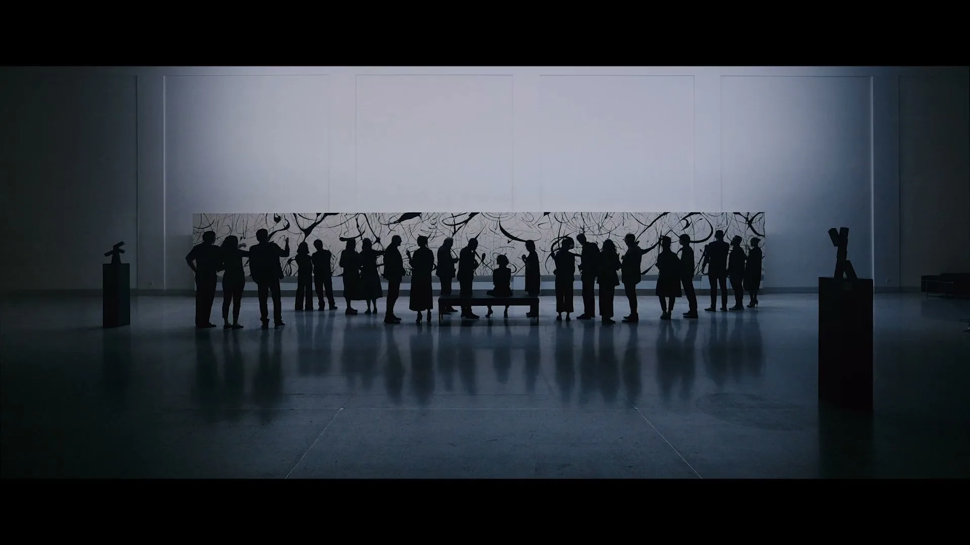 A diverse group of people are silhouetted, standing in a line in front of a large abstract painting in a modern art gallery.