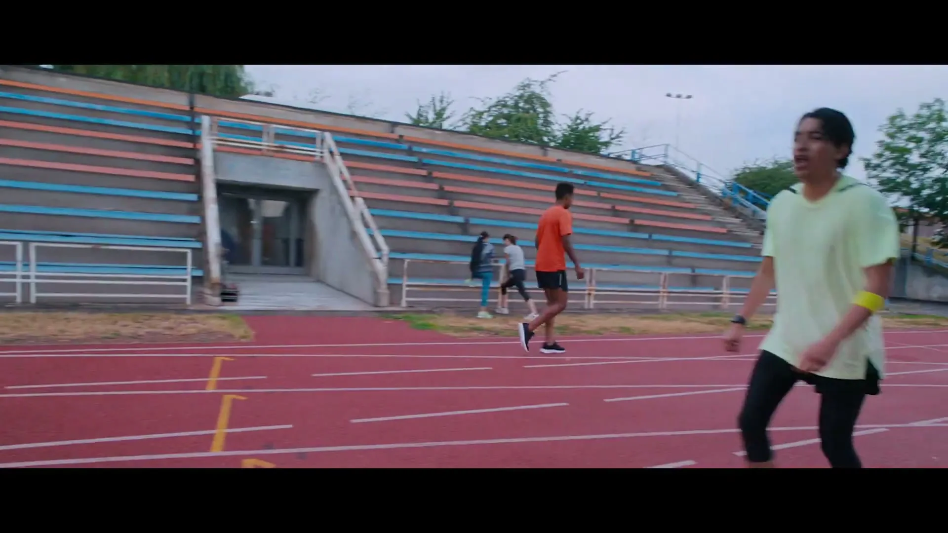 A man in a light green shirt runs on a track, then a close-up of a hand tapping an Apple Watch, followed by a man in a scout uniform looking down.