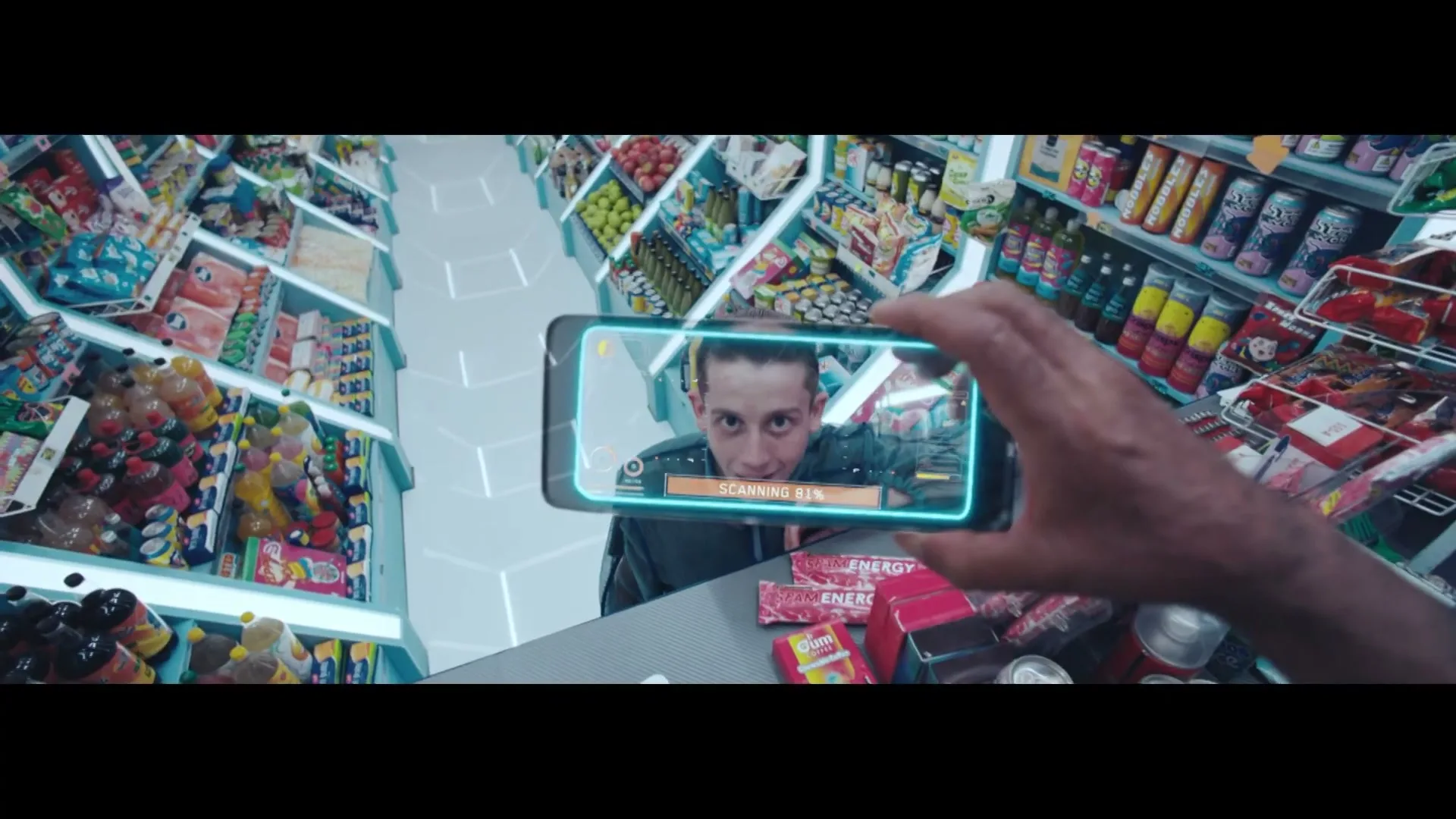 A man with an age filter applied to his face is seen through a phone screen, looking surprised in a futuristic supermarket.