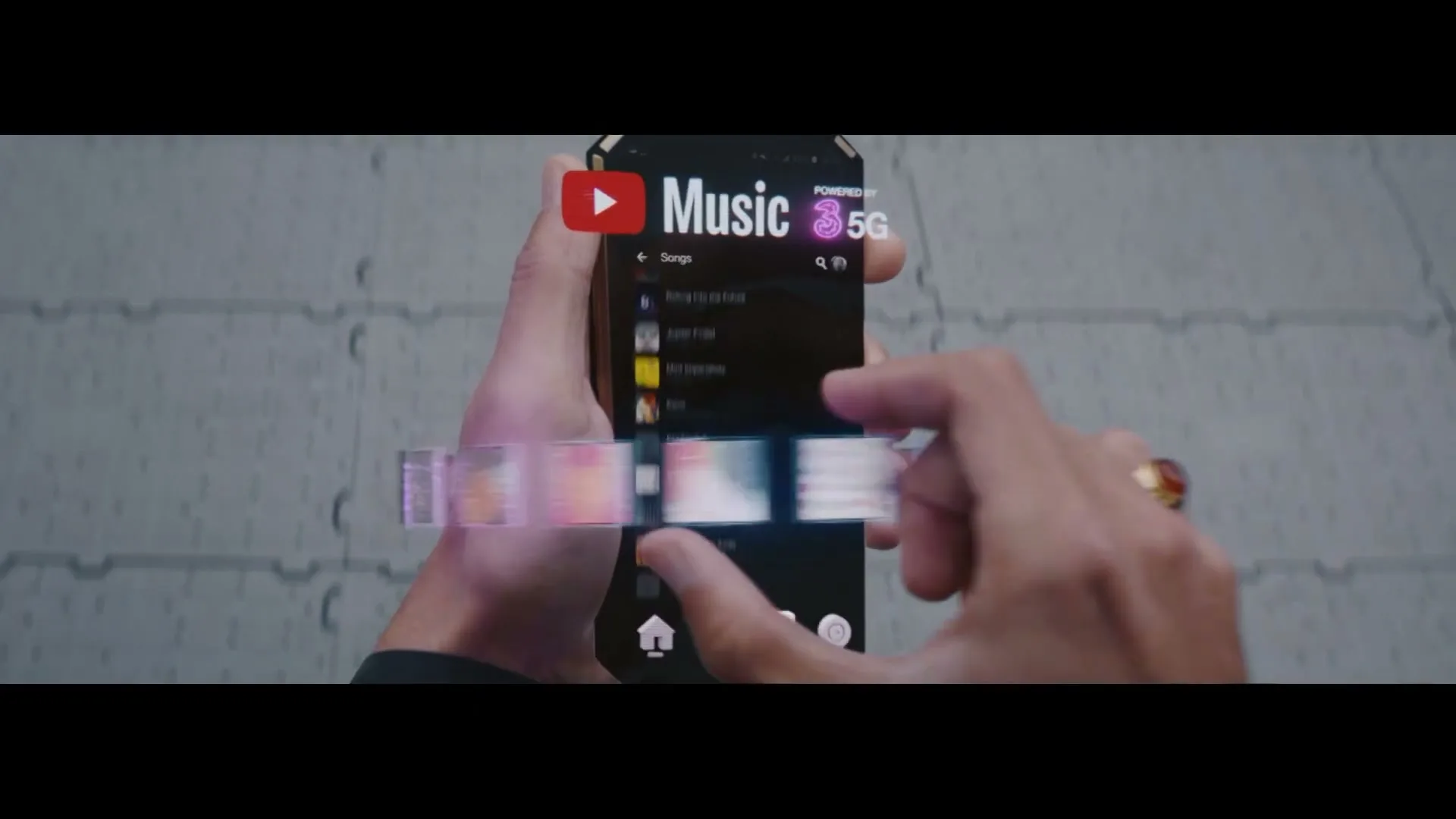 A person's hands interact with a futuristic smartphone displaying a music app with holographic elements, against a gray tiled background.