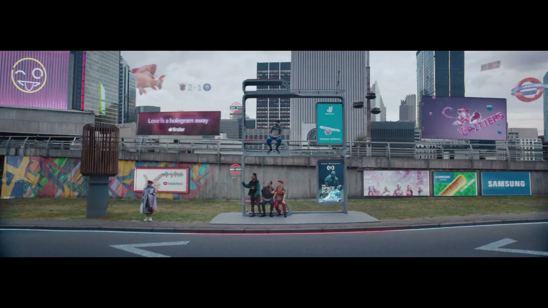 A wide shot of a futuristic city street with people at a bus stop, surrounded by holographic advertisements and a red double-decker bus passing by.
