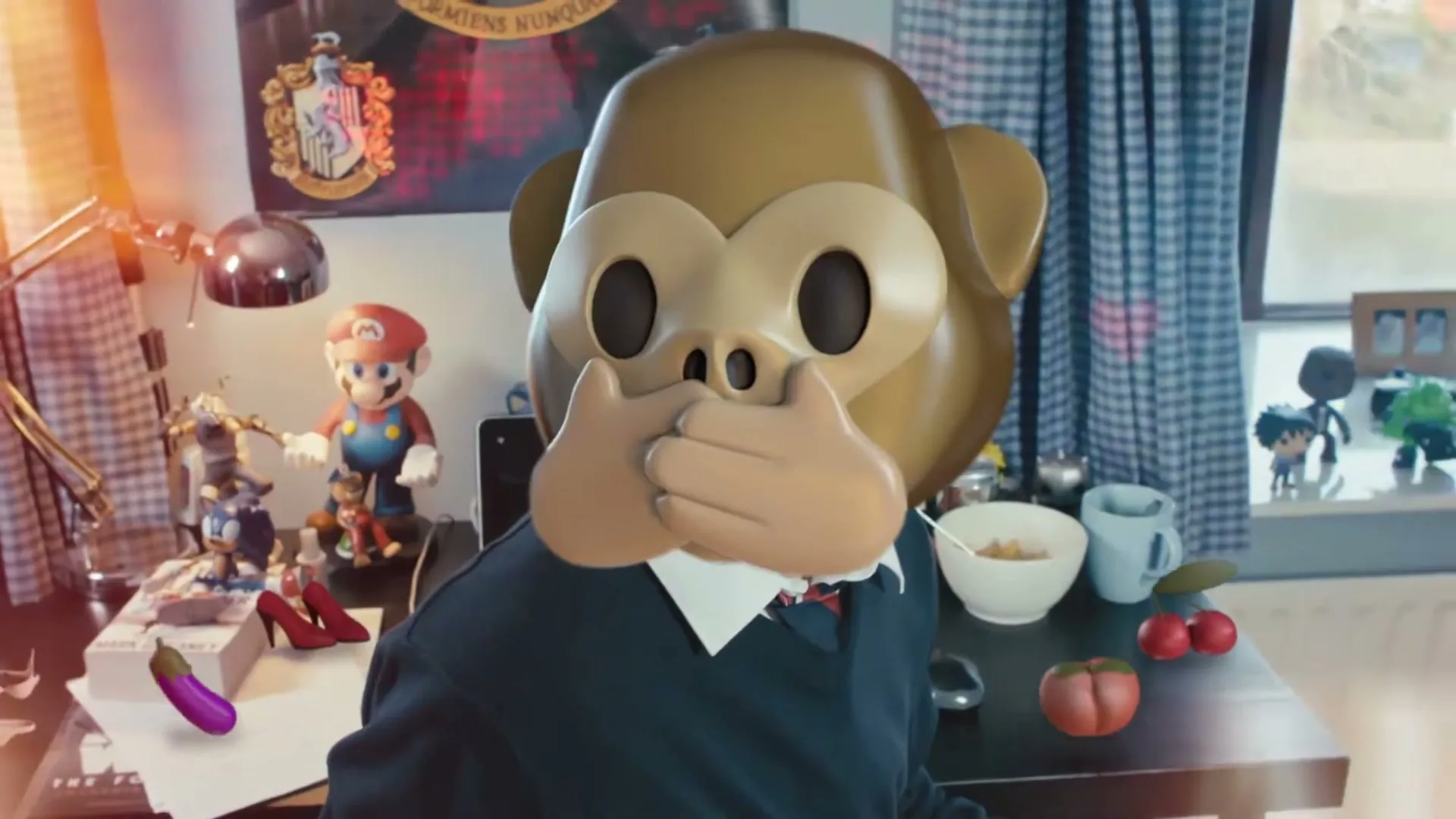 A person wearing a monkey emoji mask sits at a desk with various objects, including a Mario figurine and a dildo, in a bedroom.