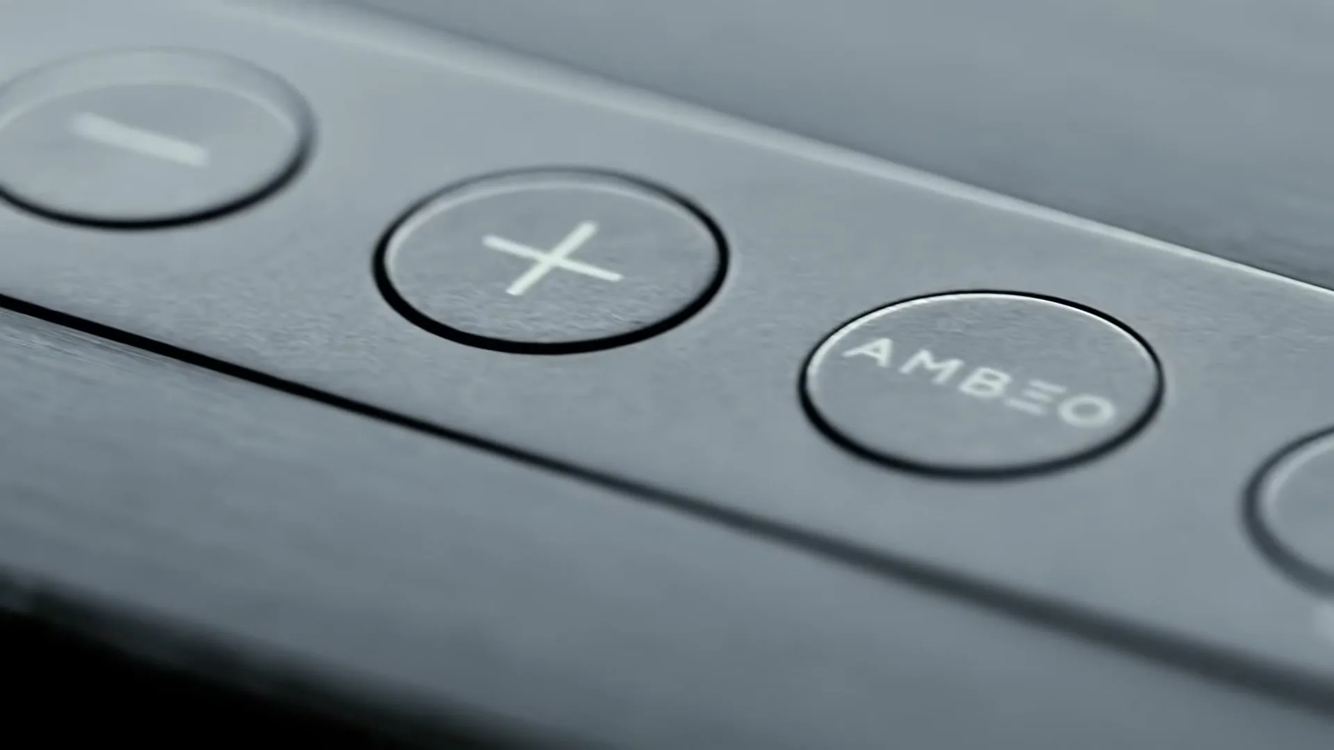A close-up shot of the top panel of a Sennheiser AMBEO soundbar, showing the volume and AMBEO buttons.