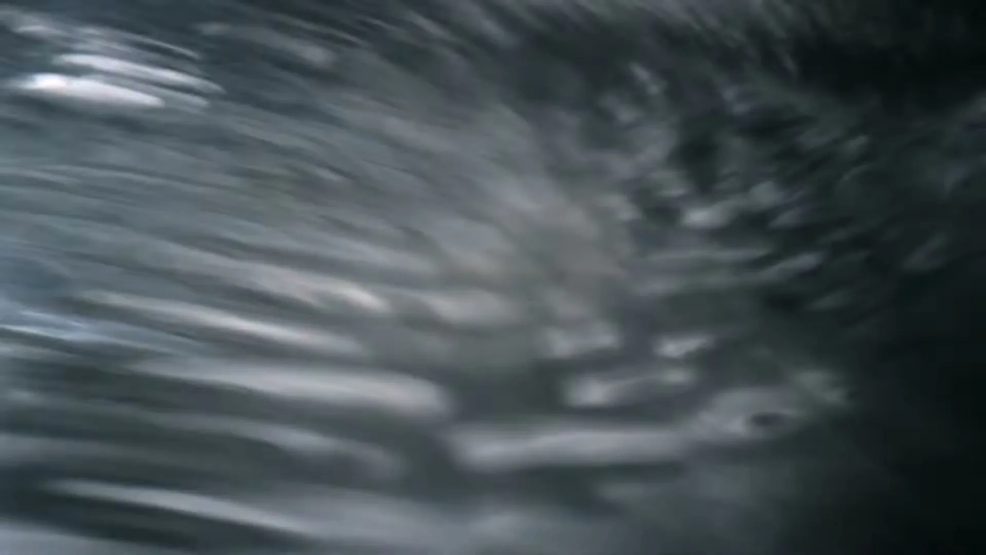 Abstract shot of light reflecting and refracting on a rippling water surface, creating dynamic, shimmering patterns.