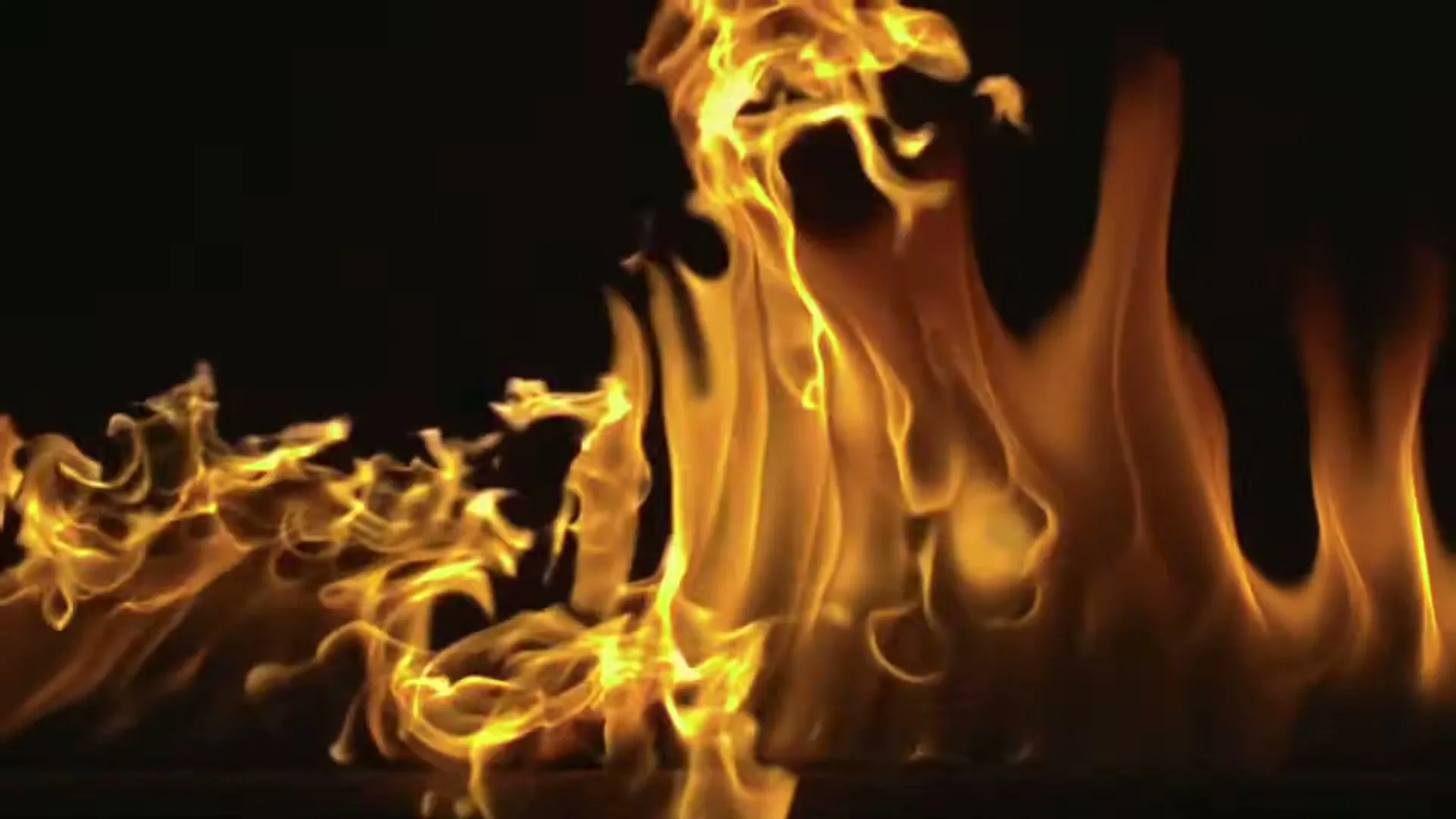 Close-up of bright orange and yellow flames dancing against a dark background, creating a dynamic and intense visual.