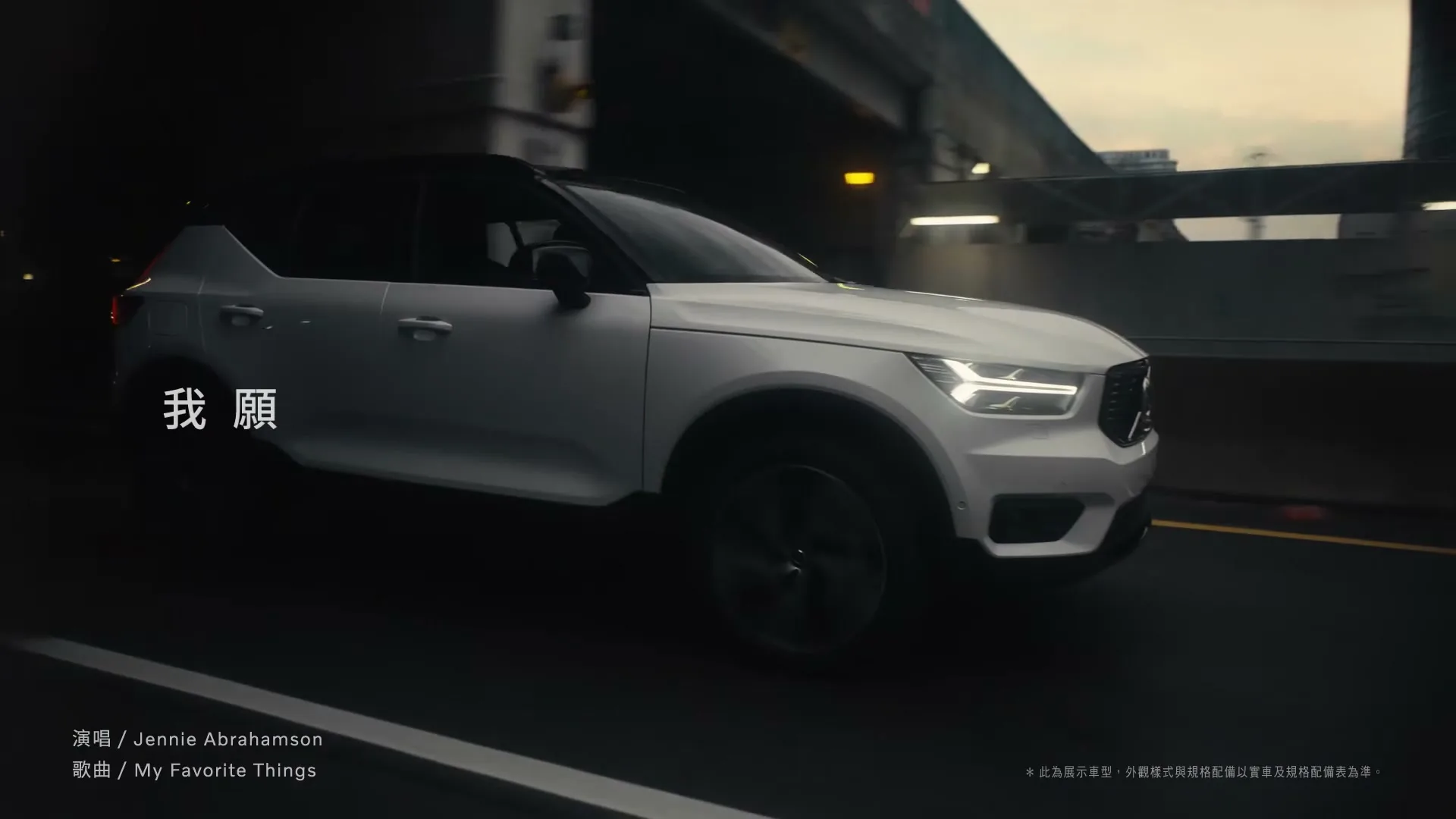A white Volvo SUV drives out of a dark tunnel into a city street at dusk, with text overlay.