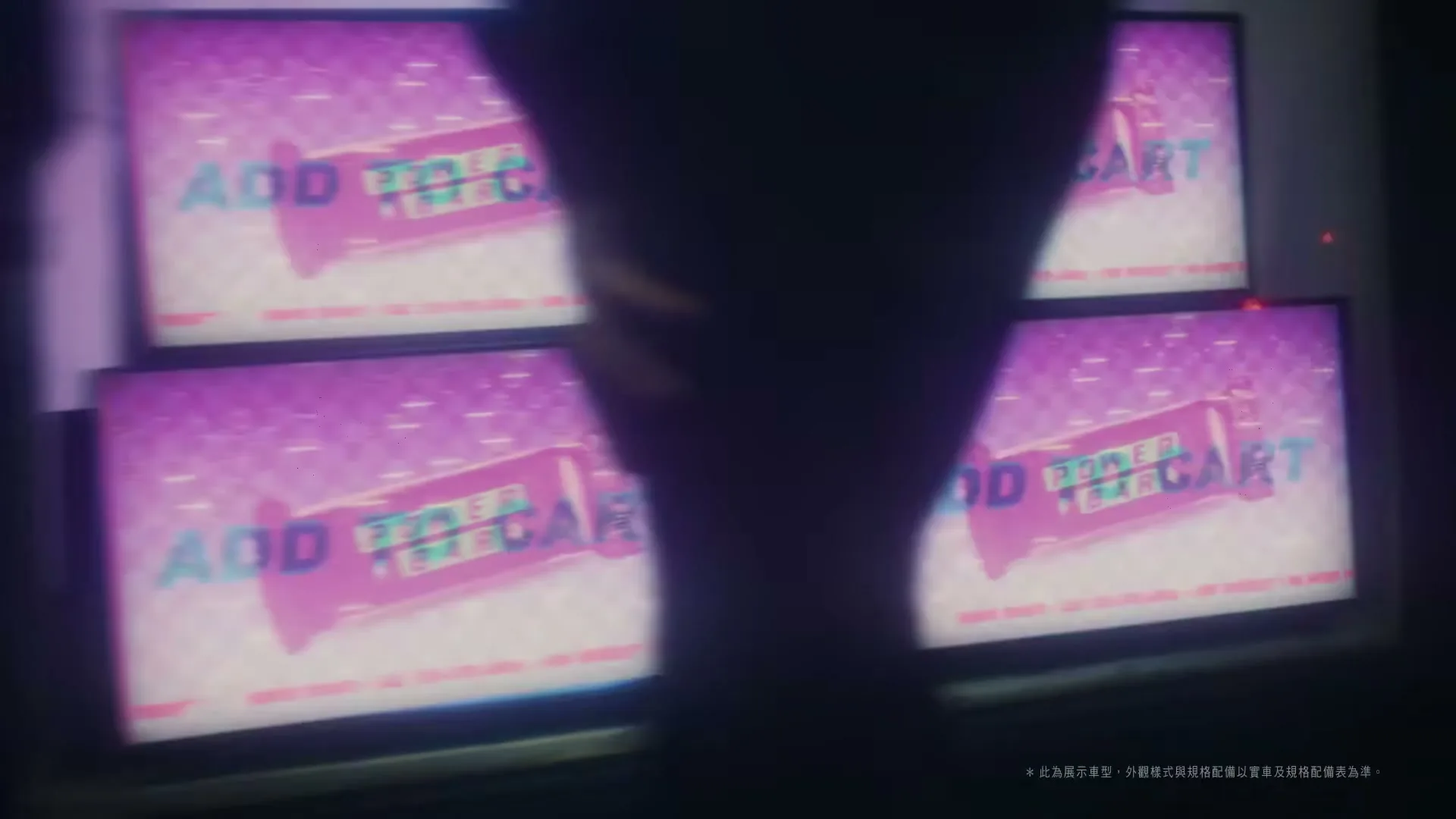 A blurry shot of multiple screens displaying various graphics, including a dollar sign and text, seen through a dark, out-of-focus foreground.