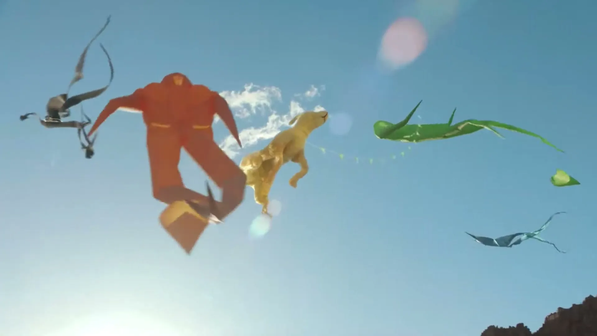 A yellow dog kite, a green dragon kite, and an orange human-like kite fly in a bright blue sky with lens flares.