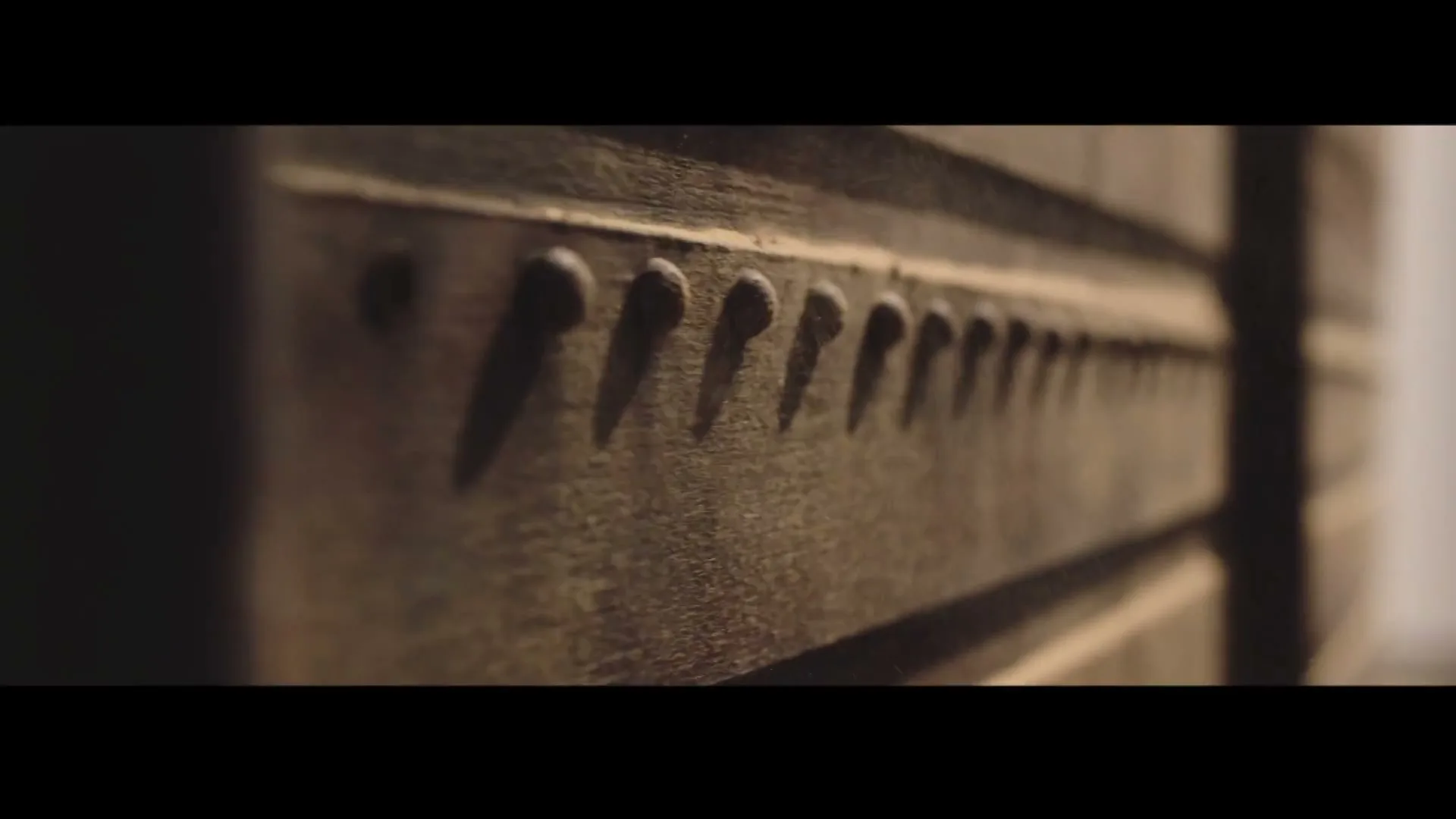 A close-up shot of a wooden box with metal studs, showing intricate details and texture, in a dimly lit interior.