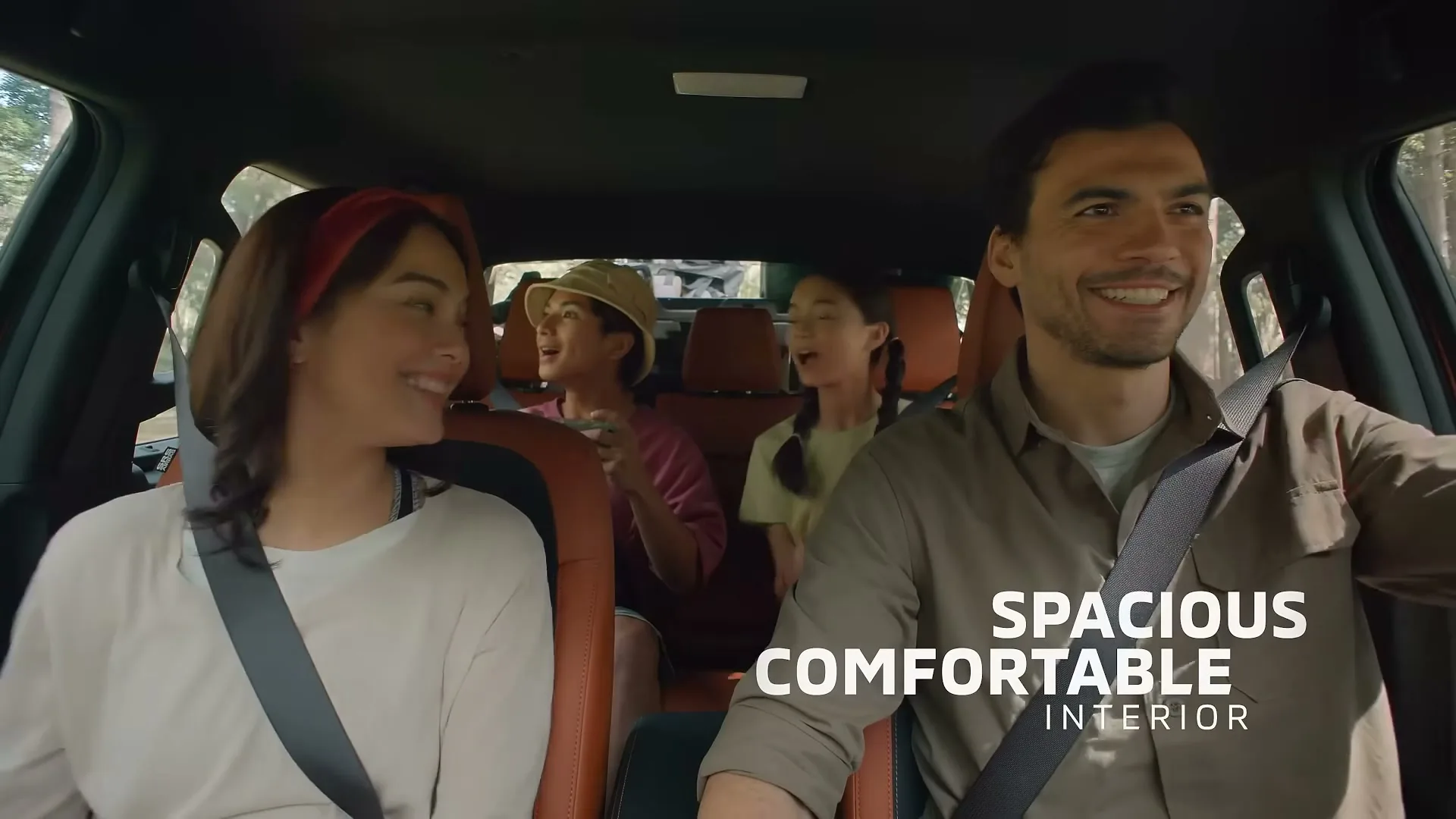 A family of four, two adults in the front and two children in the back, are happily driving in a car, with text overlay about the interior.