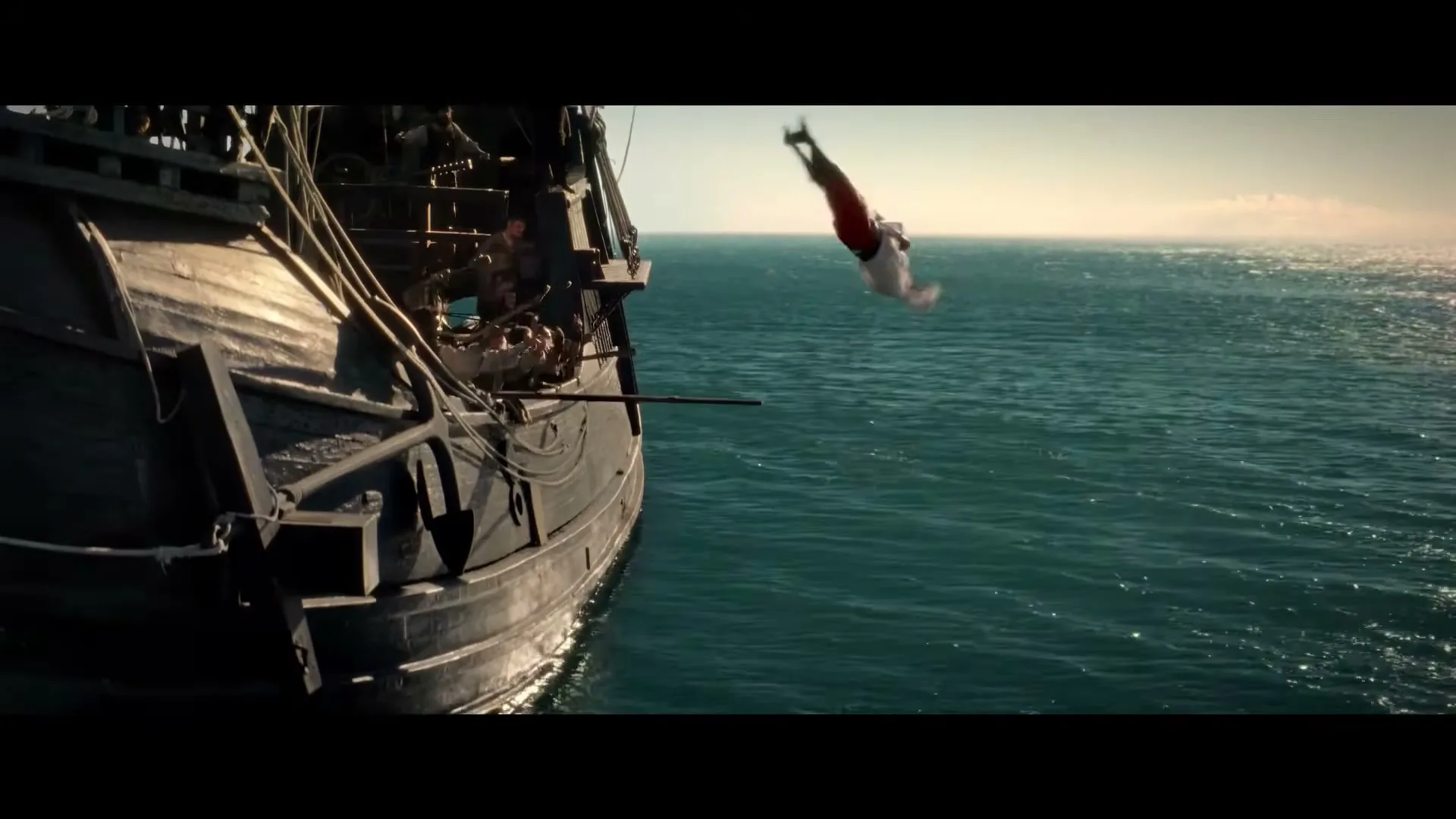 A man in pirate attire walks the plank off a large wooden ship and plunges into the vast blue ocean under a bright sky.