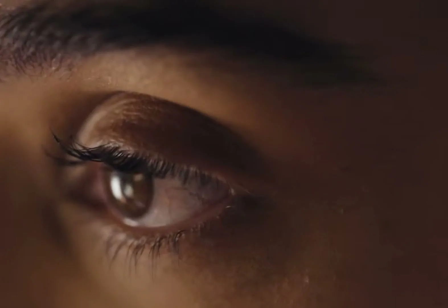 A close-up shot of a person's eye, looking intently, with warm, soft lighting on their face.