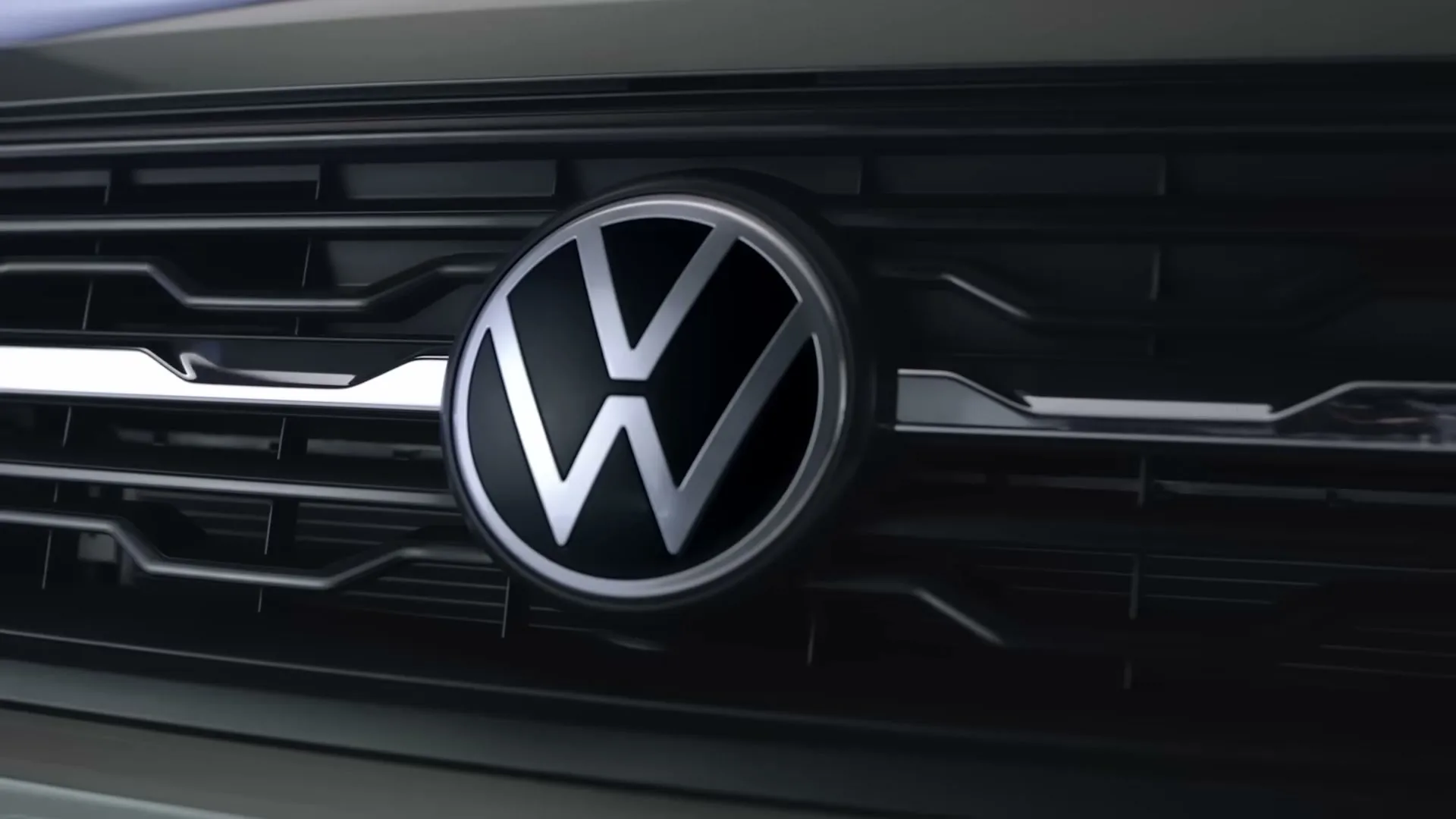 A close-up shot of the Volkswagen logo on the front grille of a car, showcasing its metallic details.