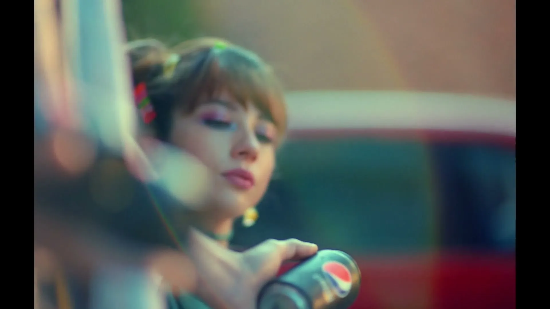 A young woman with colorful makeup and hair clips holds a Pepsi Black can, looking thoughtful in an outdoor setting.
