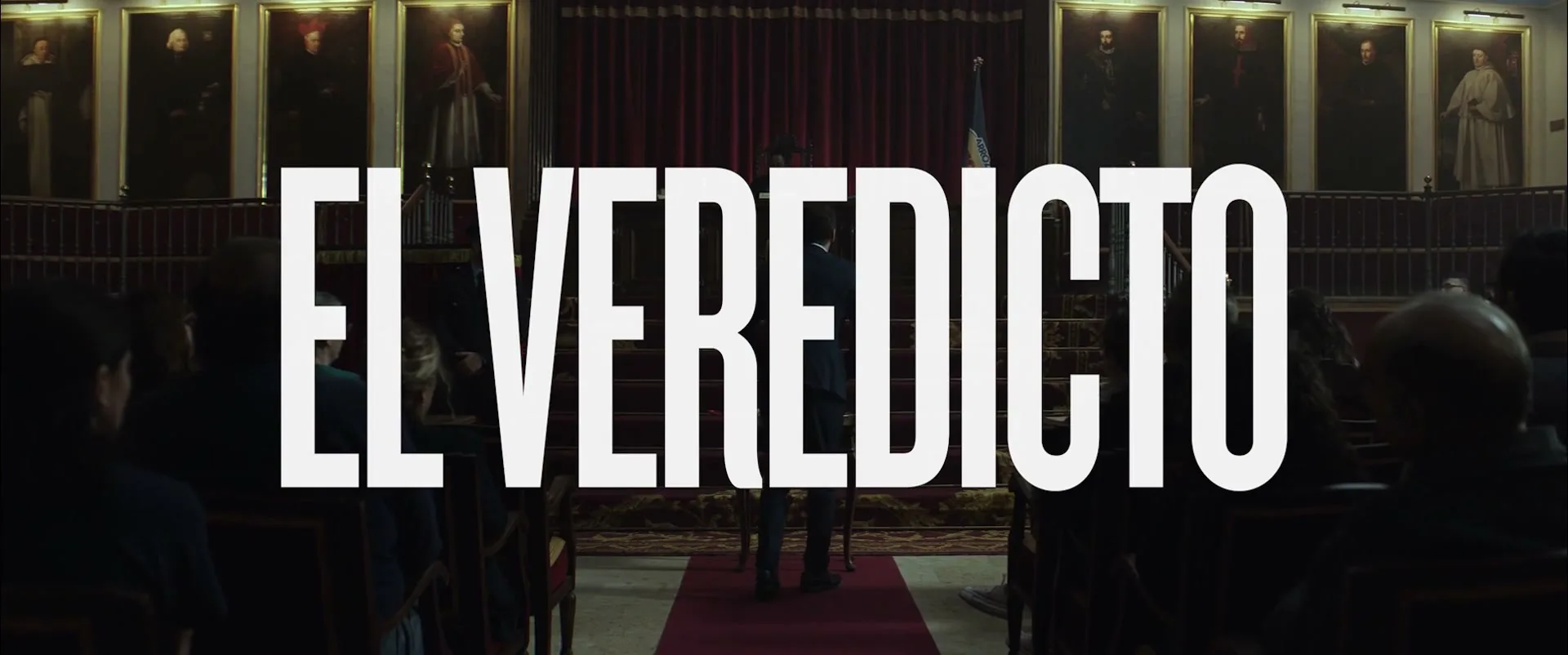 A man in a suit walks down a red carpet in a grand hall with portraits on the walls, as large white text "EL VEREDICTO" overlays the scene.