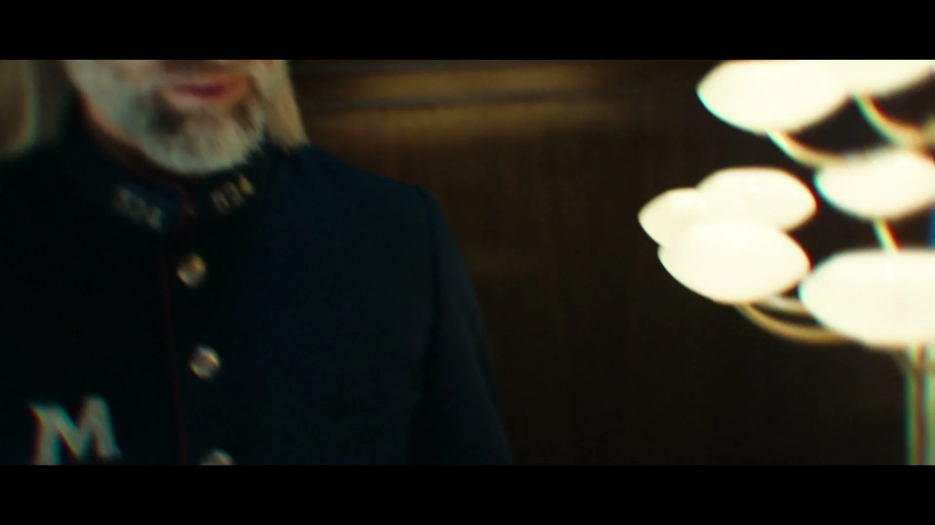 A man with long grey hair and a beard, wearing a dark uniform, looks at the camera and then down at a Magnum Classic ice cream bar in a silver bowl of ice.