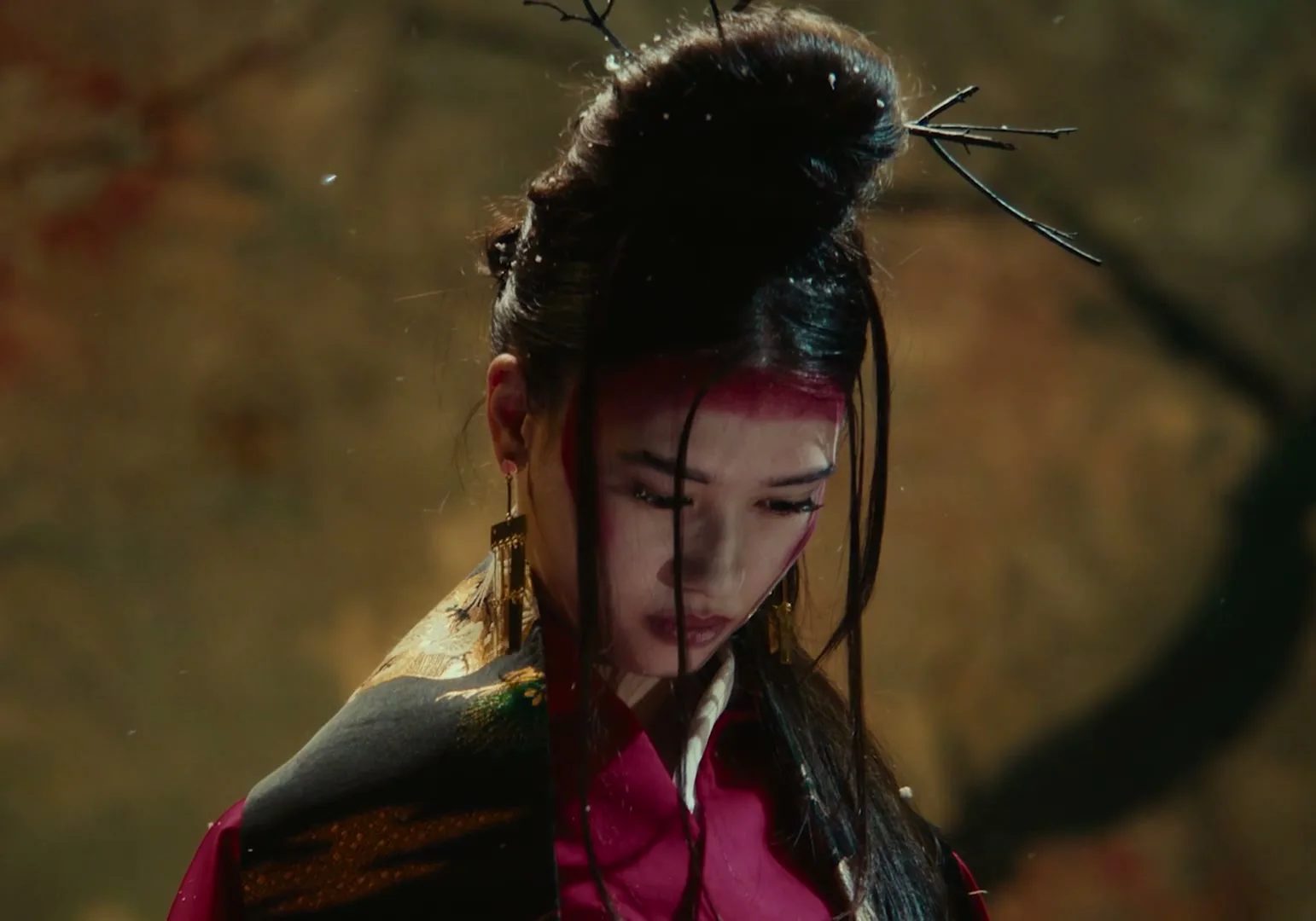 A young woman with elaborate hair and makeup, wearing traditional Japanese attire, looks down with a somber expression as snow falls around her.