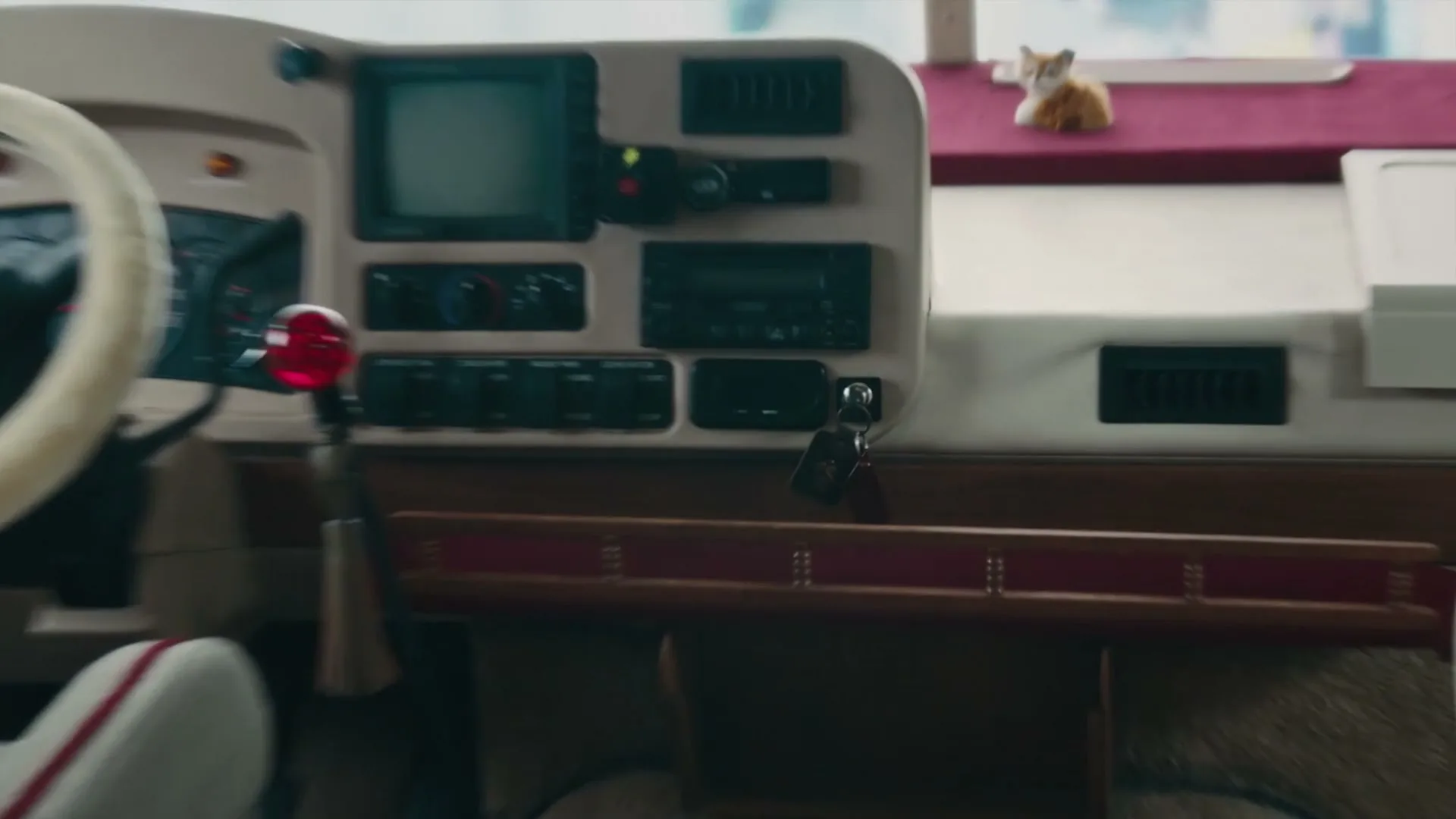 A close-up shot of a motorhome's dashboard, featuring a steering wheel, various controls, and a small fox figurine on top.