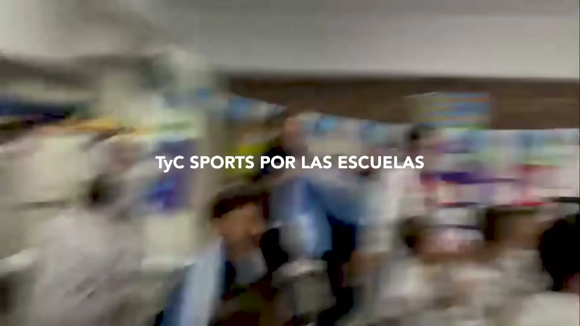 A group of excited children in white lab coats jump and cheer in a classroom decorated with blue and white flags.