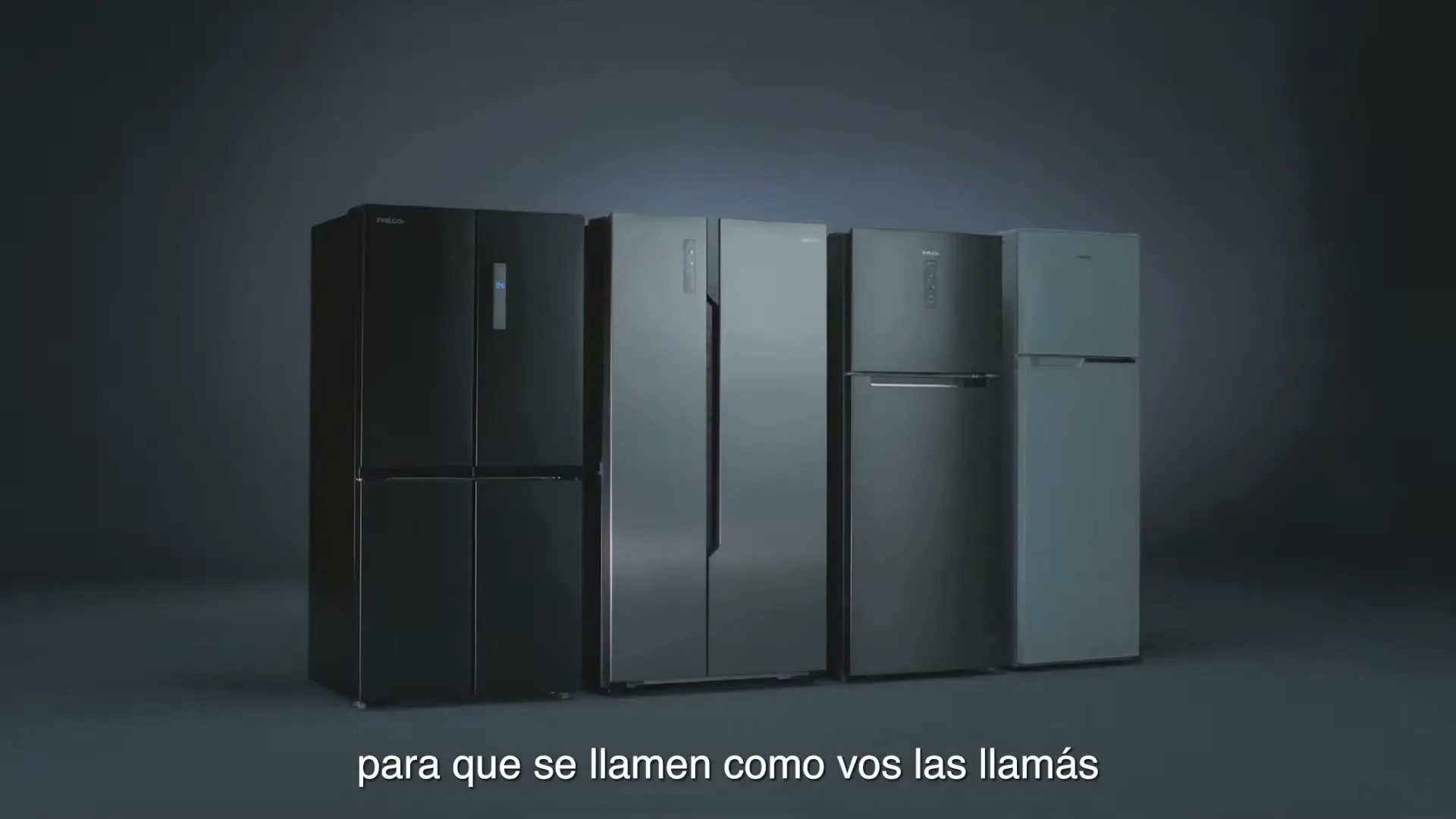A row of four modern refrigerators, varying in size and shade of gray, are displayed on a dark gray surface in a studio void.