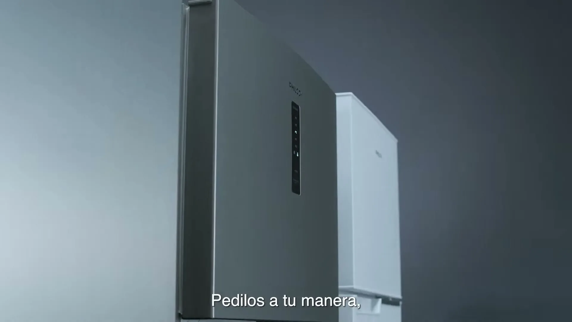 A silver Philco refrigerator with a digital display is shown in a clean single shot, with a white refrigerator partially visible in the background.