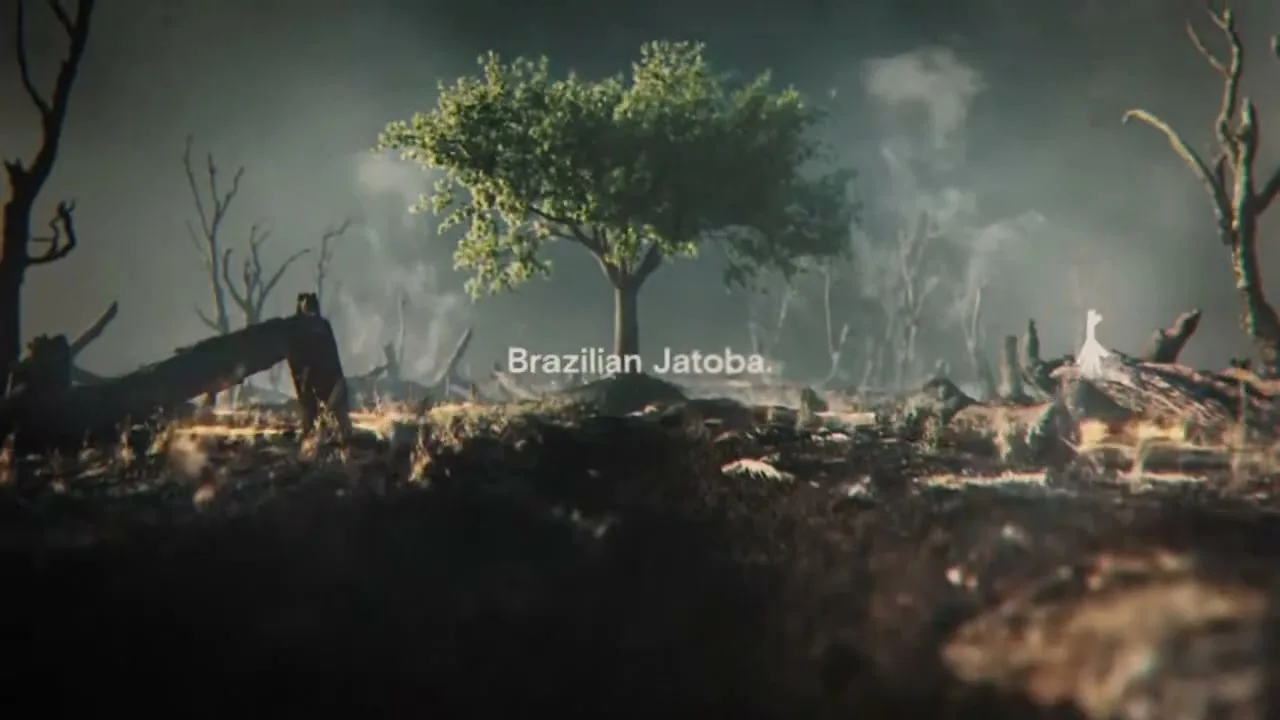 A single green tree stands in a desolate, burnt landscape with smoke rising, as text appears on screen.