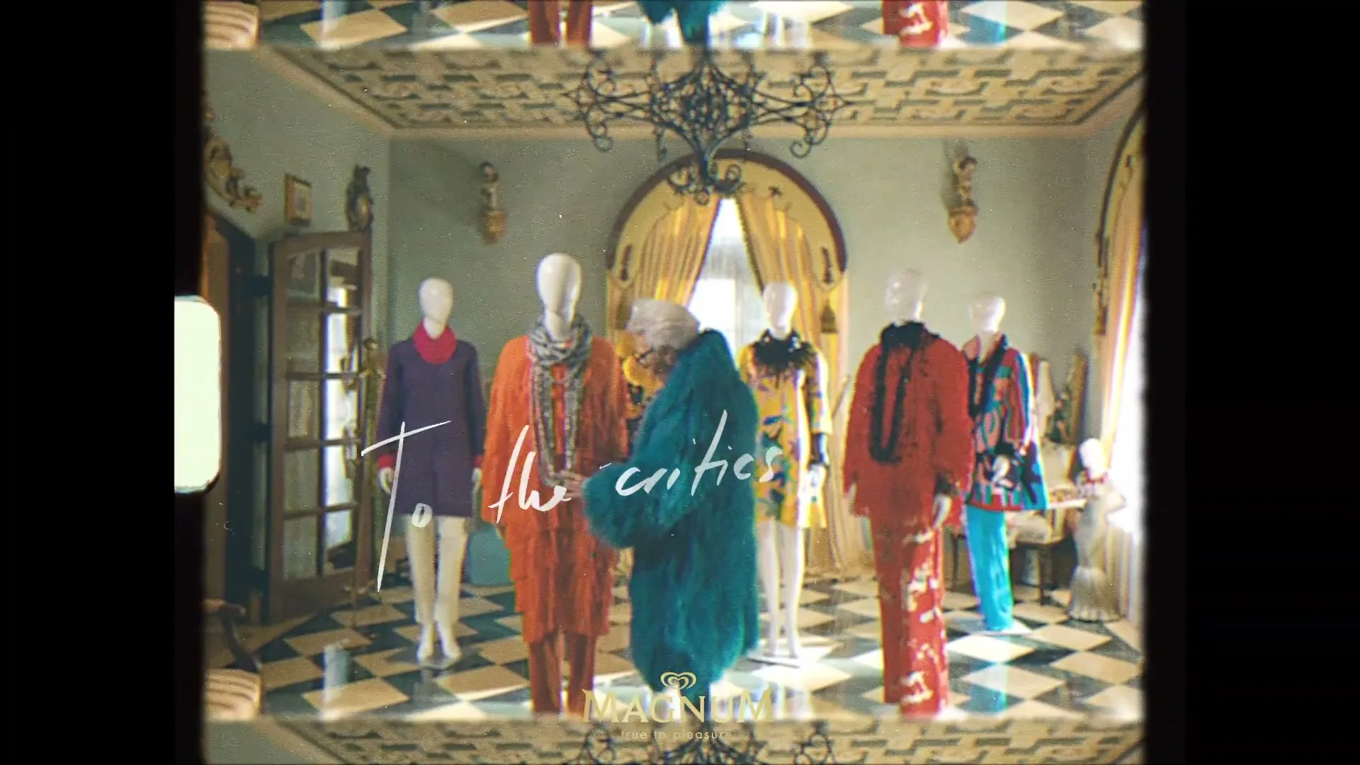 Iris Apfel, an elderly woman in a blue fur coat, stands among mannequins dressed in colorful outfits in a lavish room, as the camera slowly zooms in.