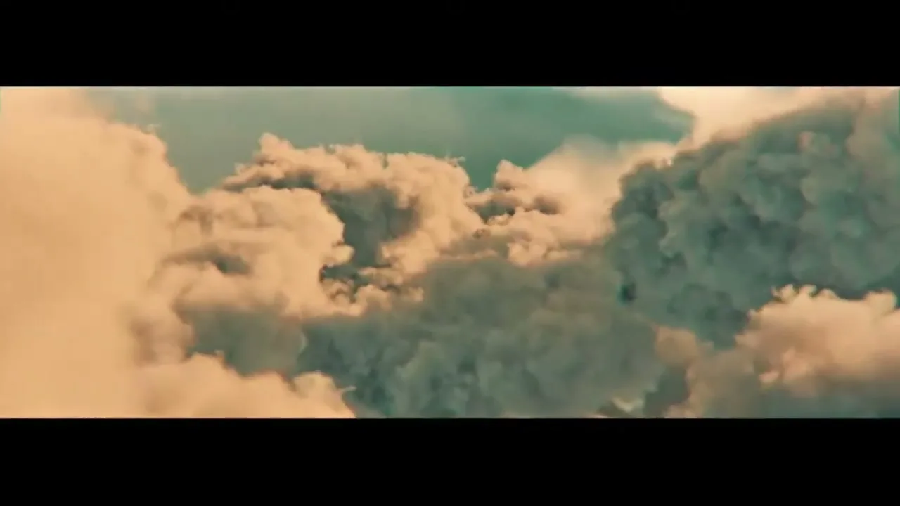 A wide shot of fluffy, golden-hued clouds against a teal sky, with the camera moving through them.