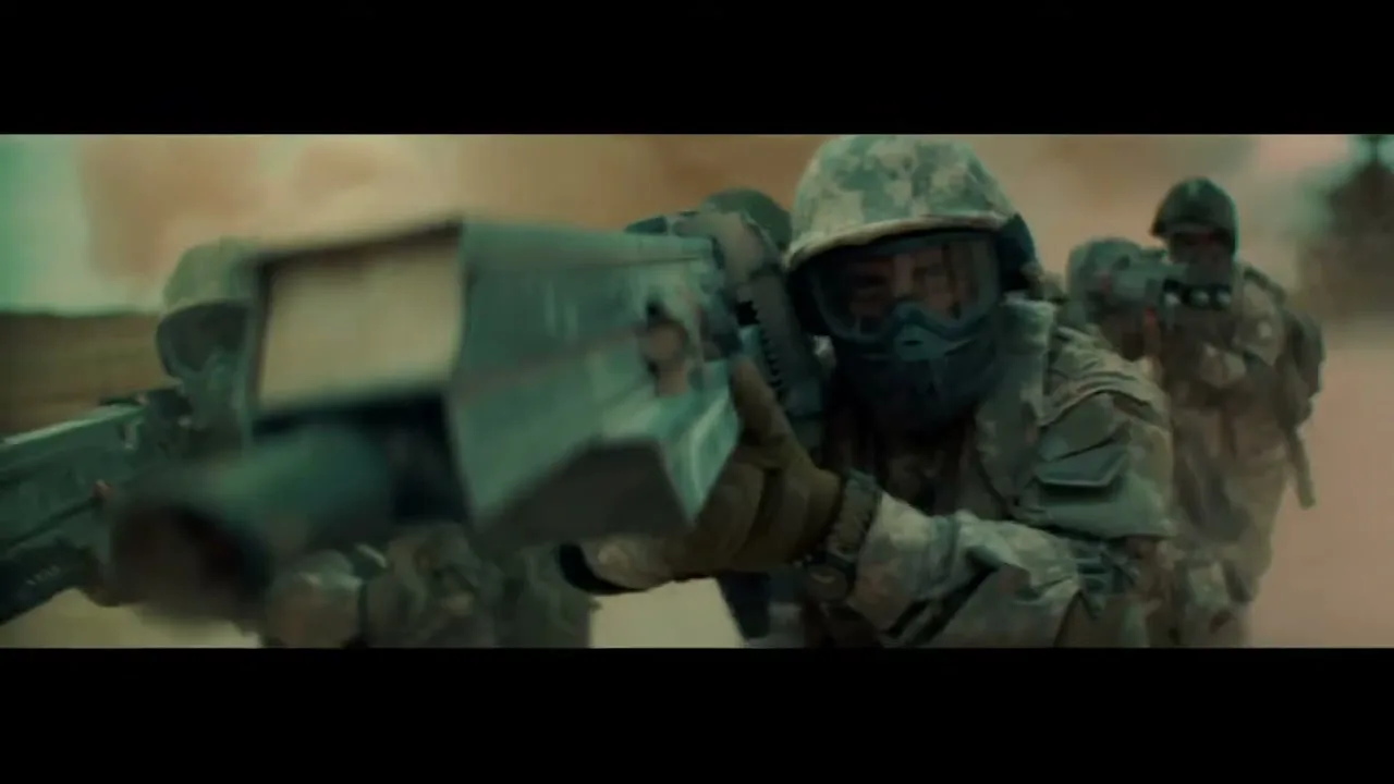 A group of soldiers in camouflage gear and helmets move forward through a dusty, smoky environment, aiming their weapons.